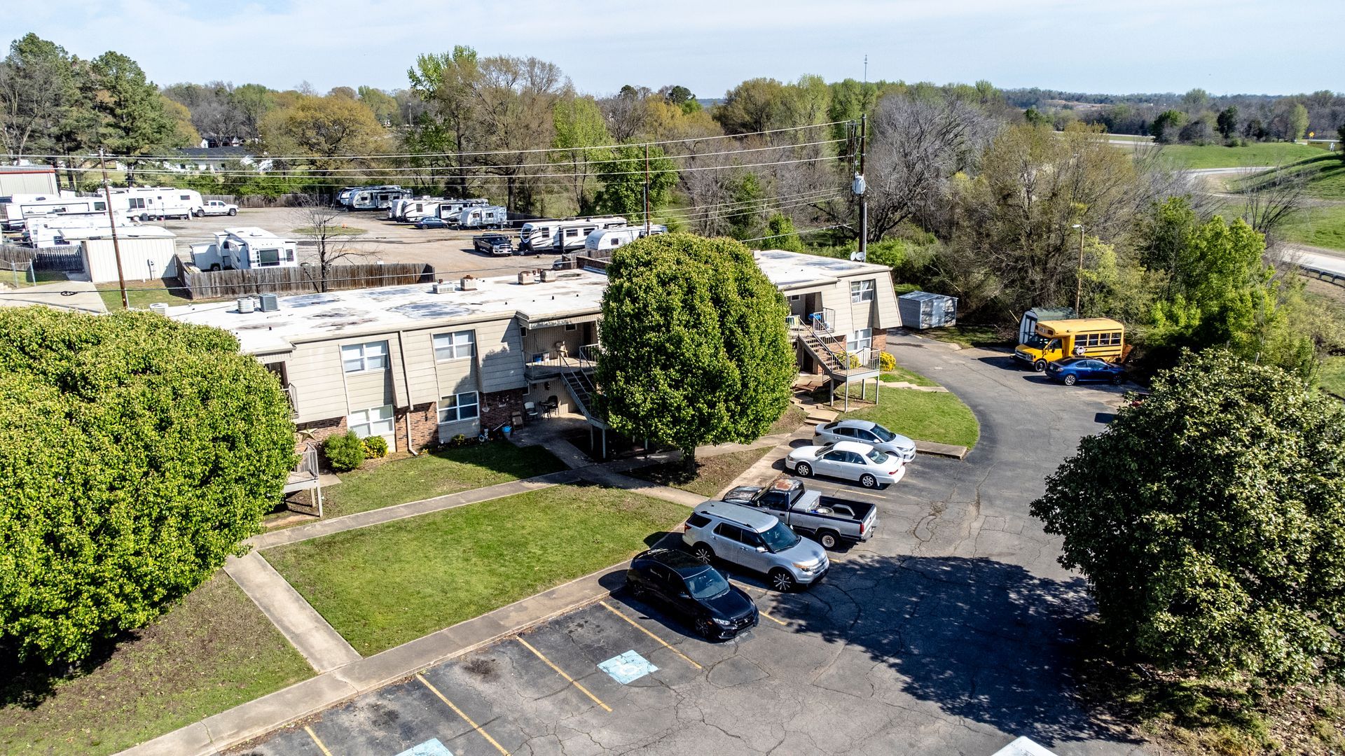 An aerial view of a parking lot filled with cars and a school bus.