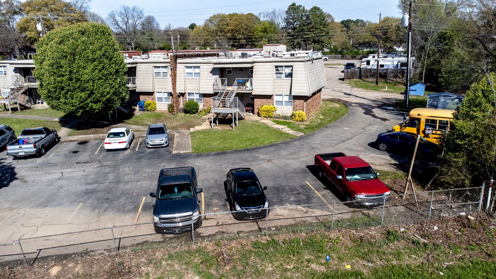 An aerial view of a parking lot with cars parked in front of a building.