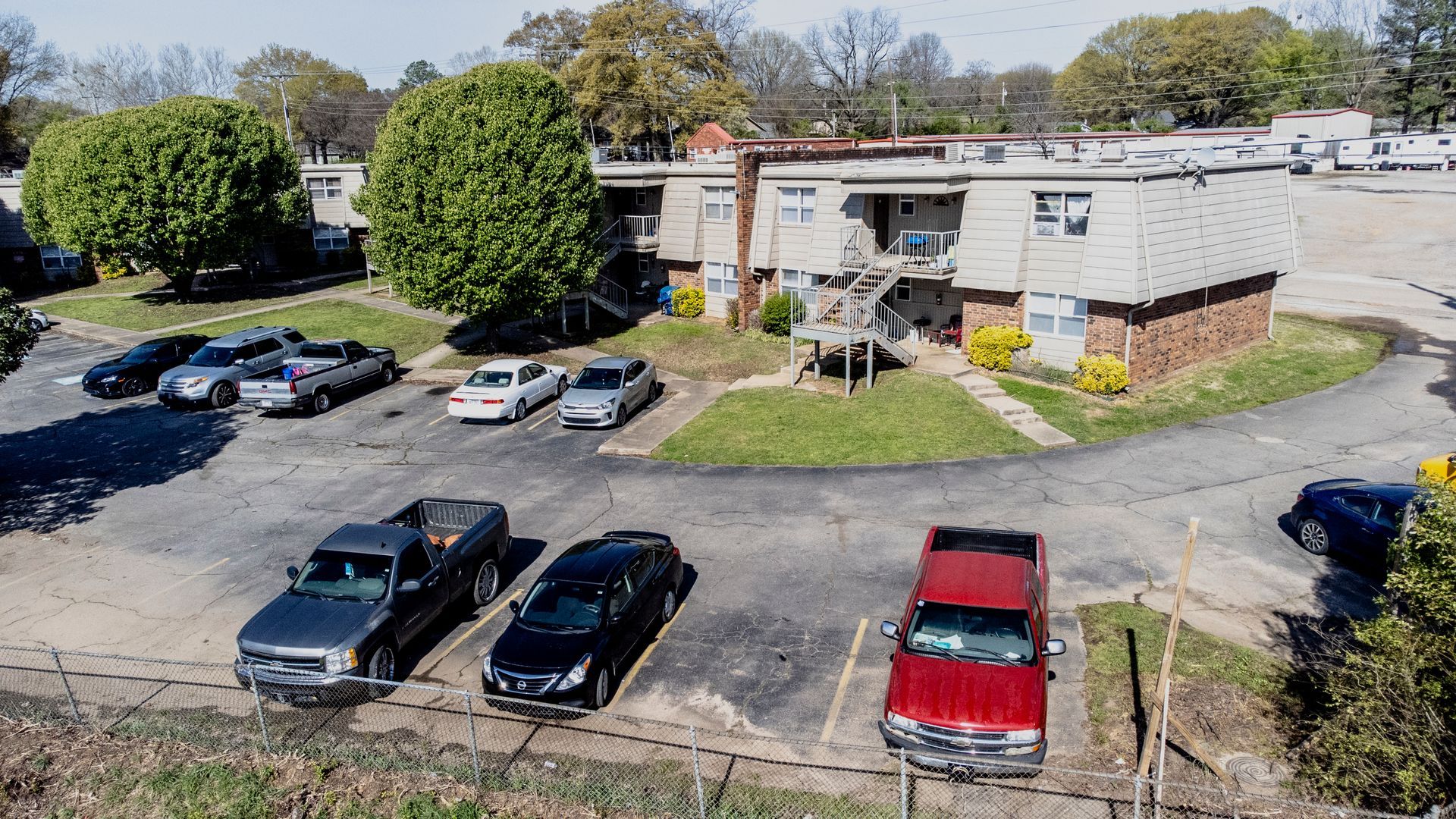 An aerial view of a parking lot with cars parked in front of a building.
