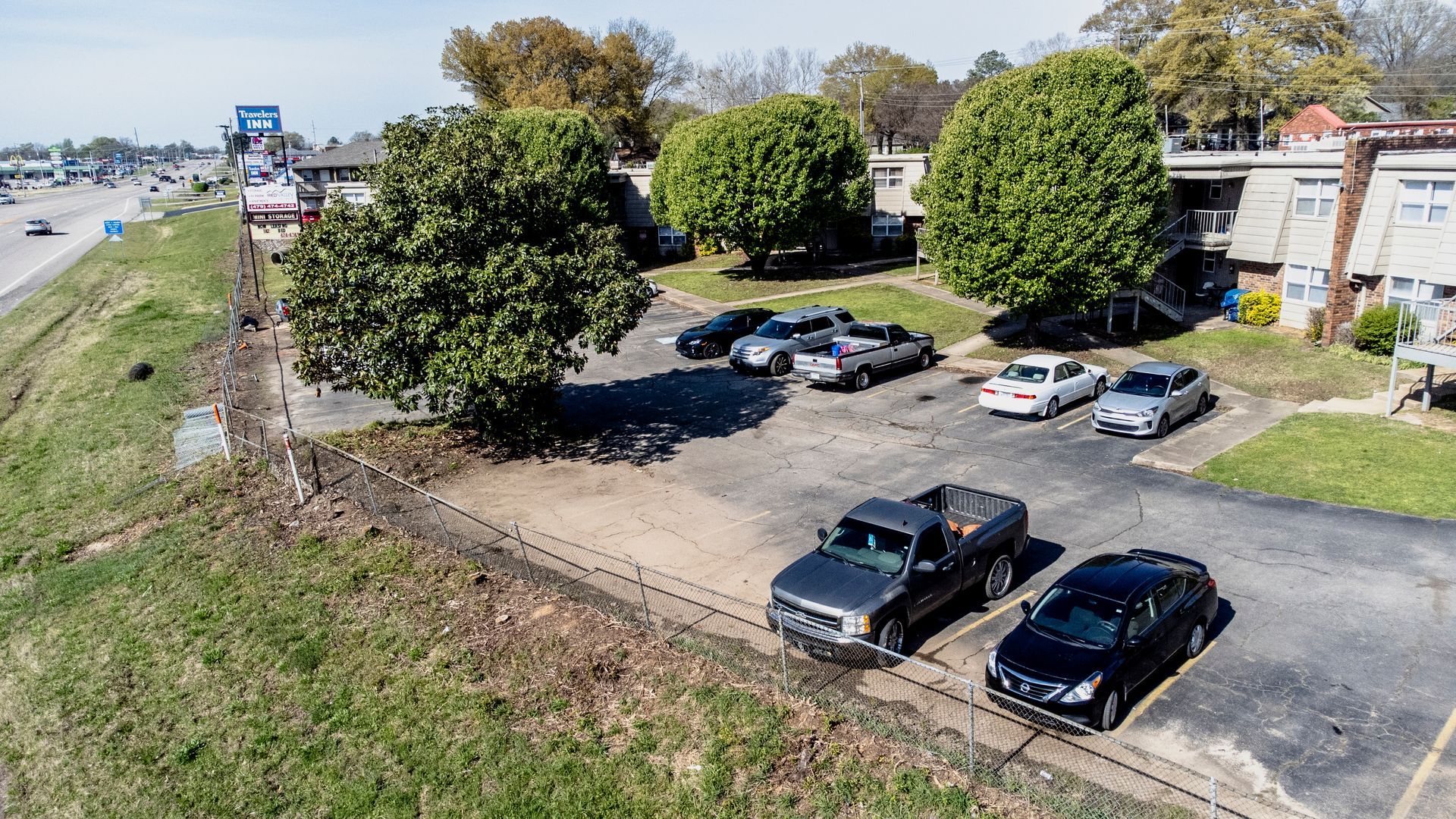 An aerial view of a parking lot with cars parked in front of a building.