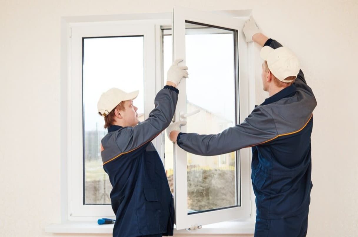 Two Men Are Installing A Window In A Room — Northern Glazing Glass & Aluminium In Smithfield, QLD