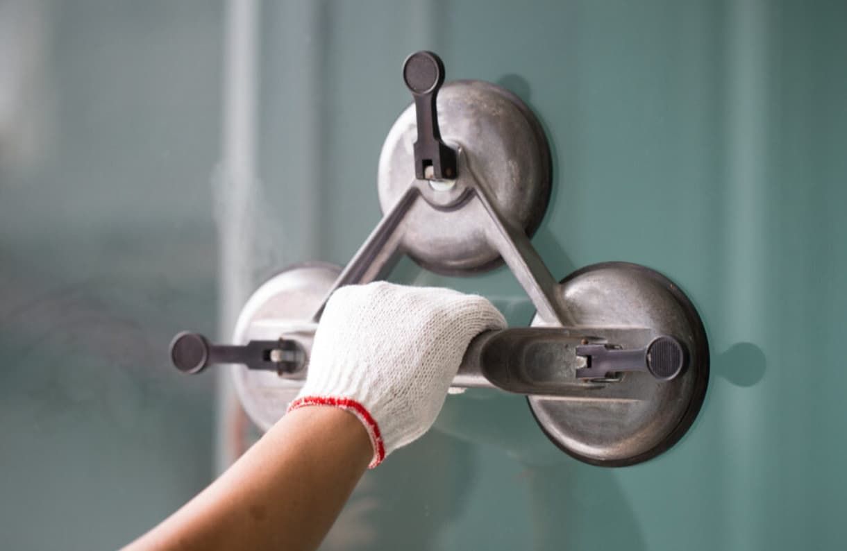 A Person Is Using A Suction Cup To Lift A Glass Door — Northern Glazing Glass & Aluminium In Smithfield, QLD