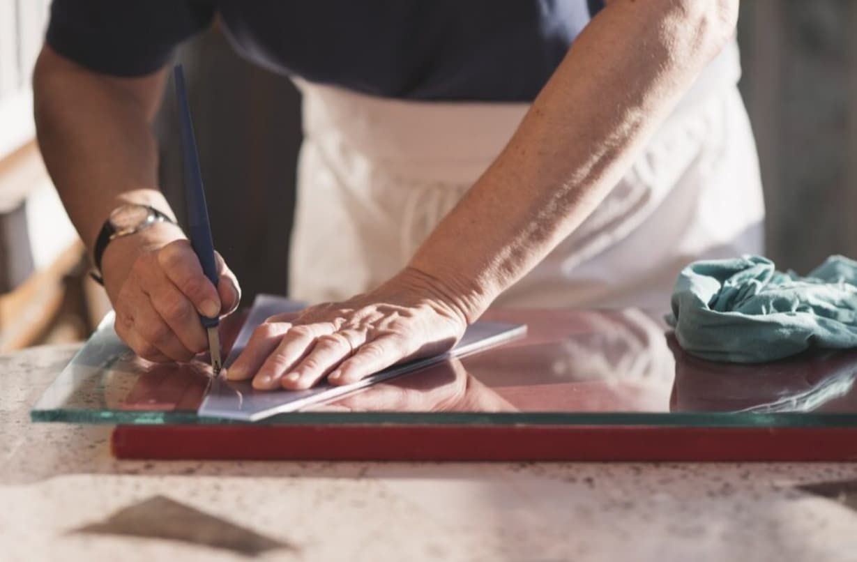 A Person Is Cutting A Piece Of Glass With A Pair Of Scissors — Northern Glazing Glass & Aluminium In Northern Beaches, QLD
