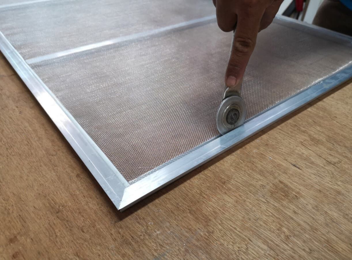 A Person Is Using A Roller To Remove A Mosquito Screen — Northern Glazing Glass & Aluminium In Northern Beaches, QLD
