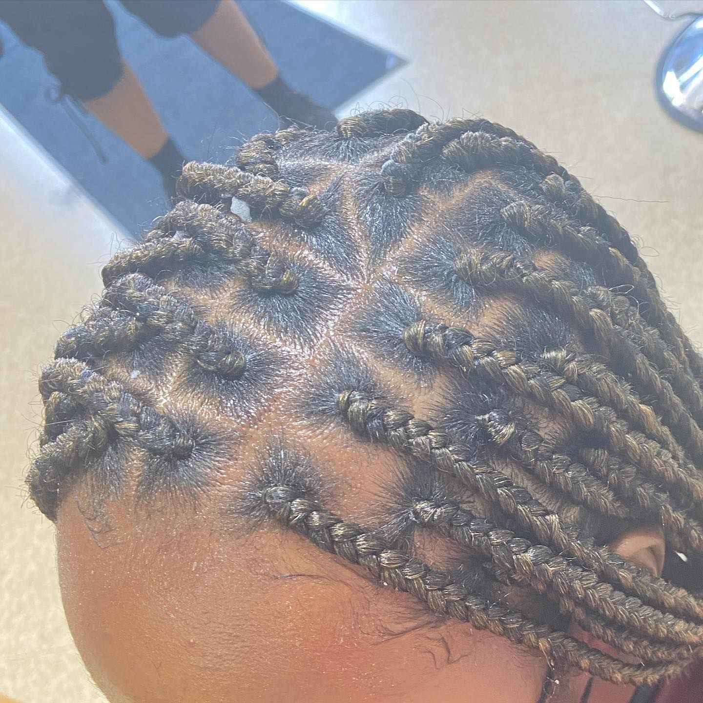 Close-up of a person's head with box braids, showing the neat parting pattern and braid texture.