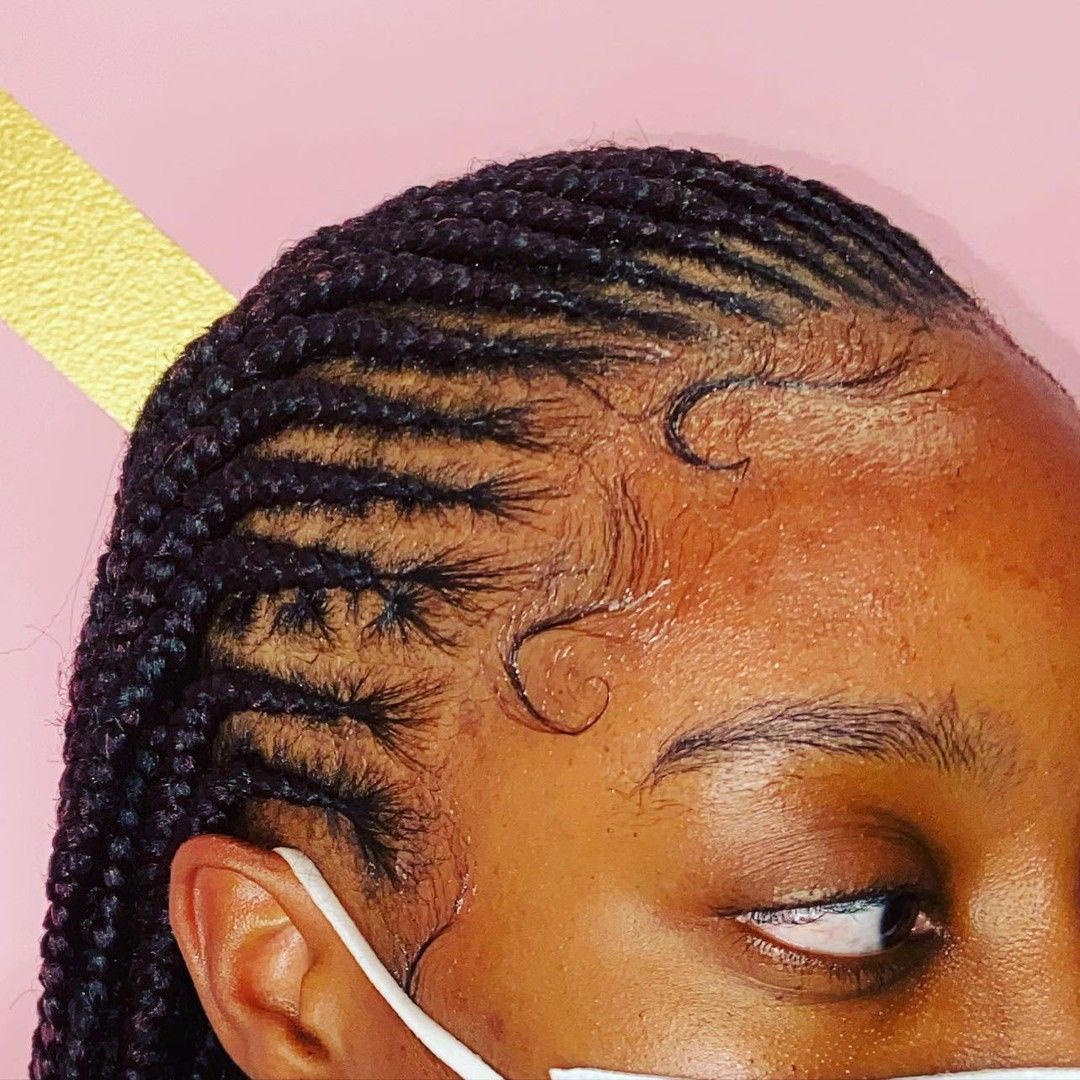 Person with braided hair and styled baby hairs; pink background.