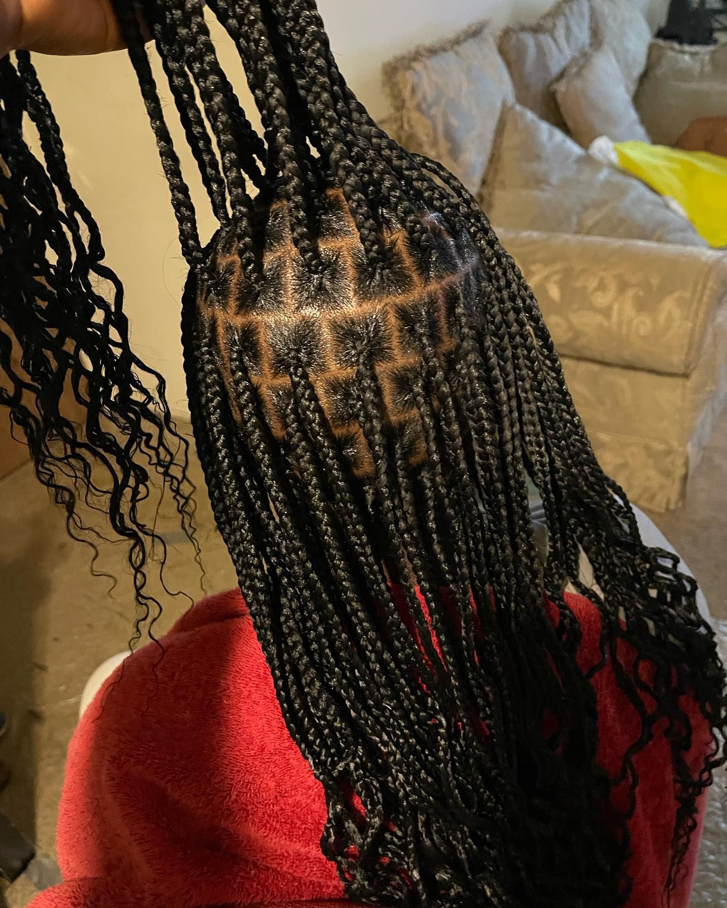 Close-up of black box braids with curly ends. Braids are parted and neatly sectioned on top of the head.