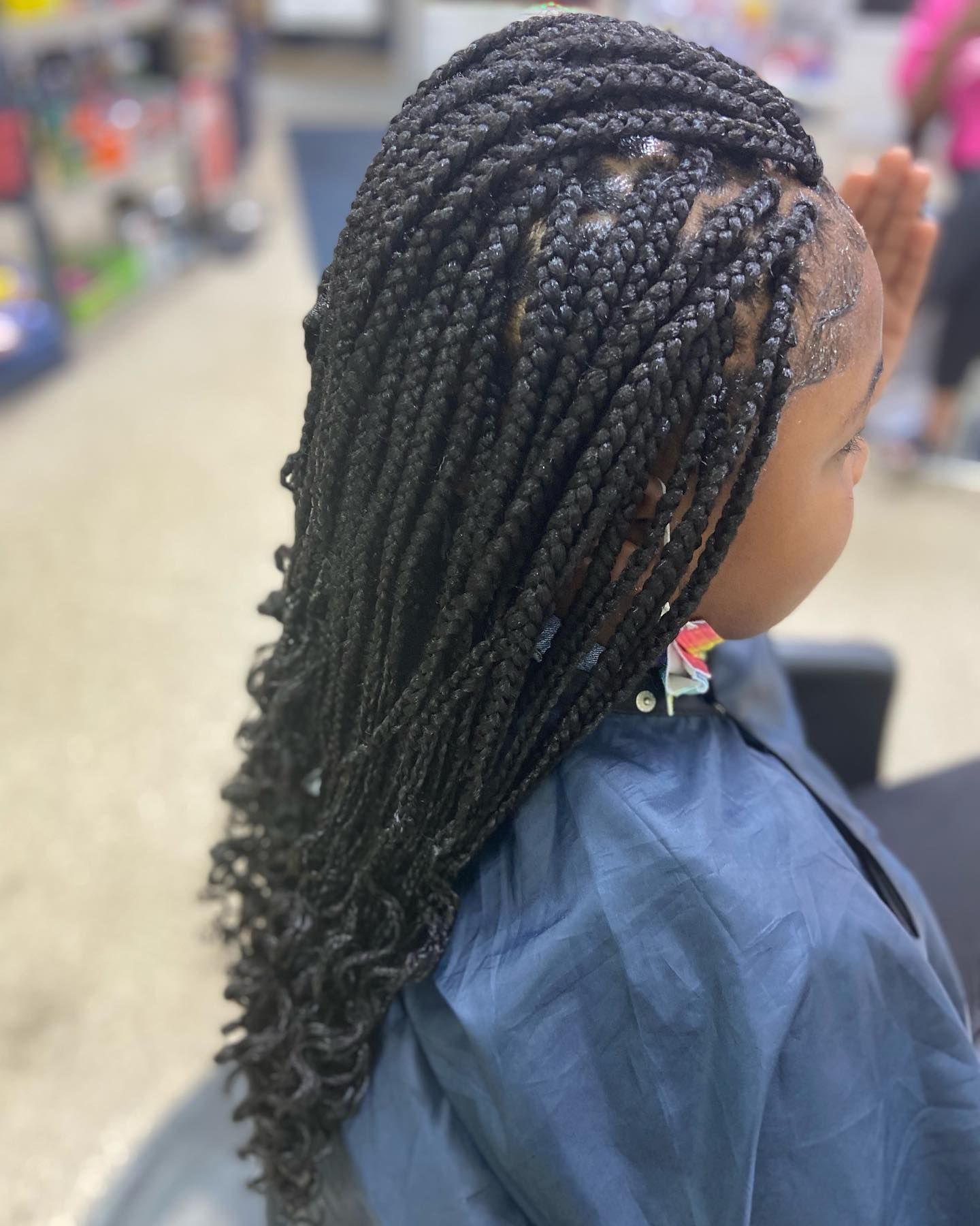 Girl with box braids and curly ends. Braids are black, hair is styled at a salon.