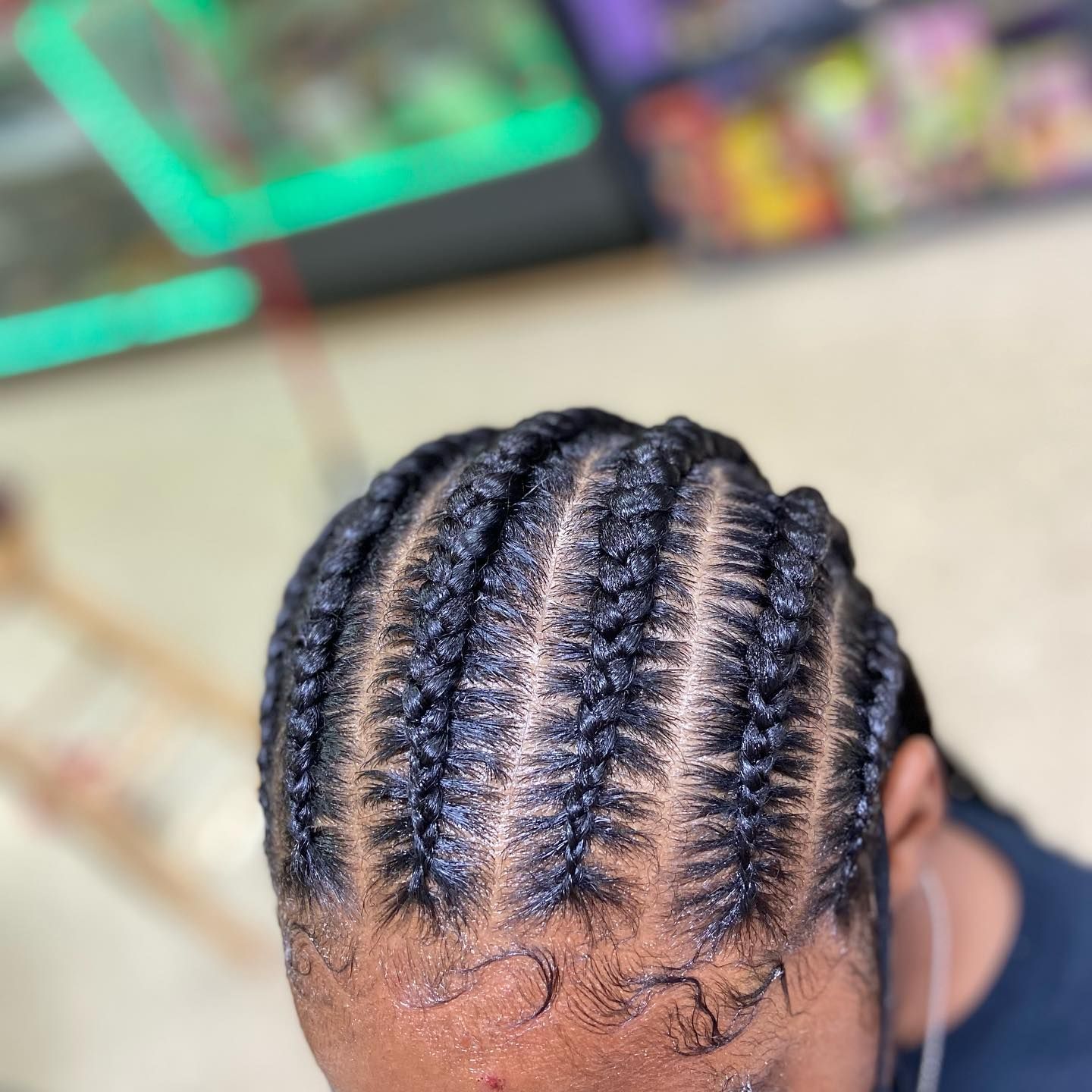 Close-up of a person's head featuring neat, dark braids styled close to the scalp.