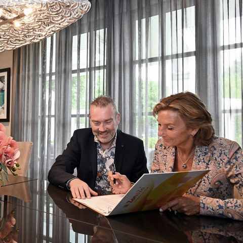 Een man en een vrouw zitten aan een tafel en kijken naar een laptop.