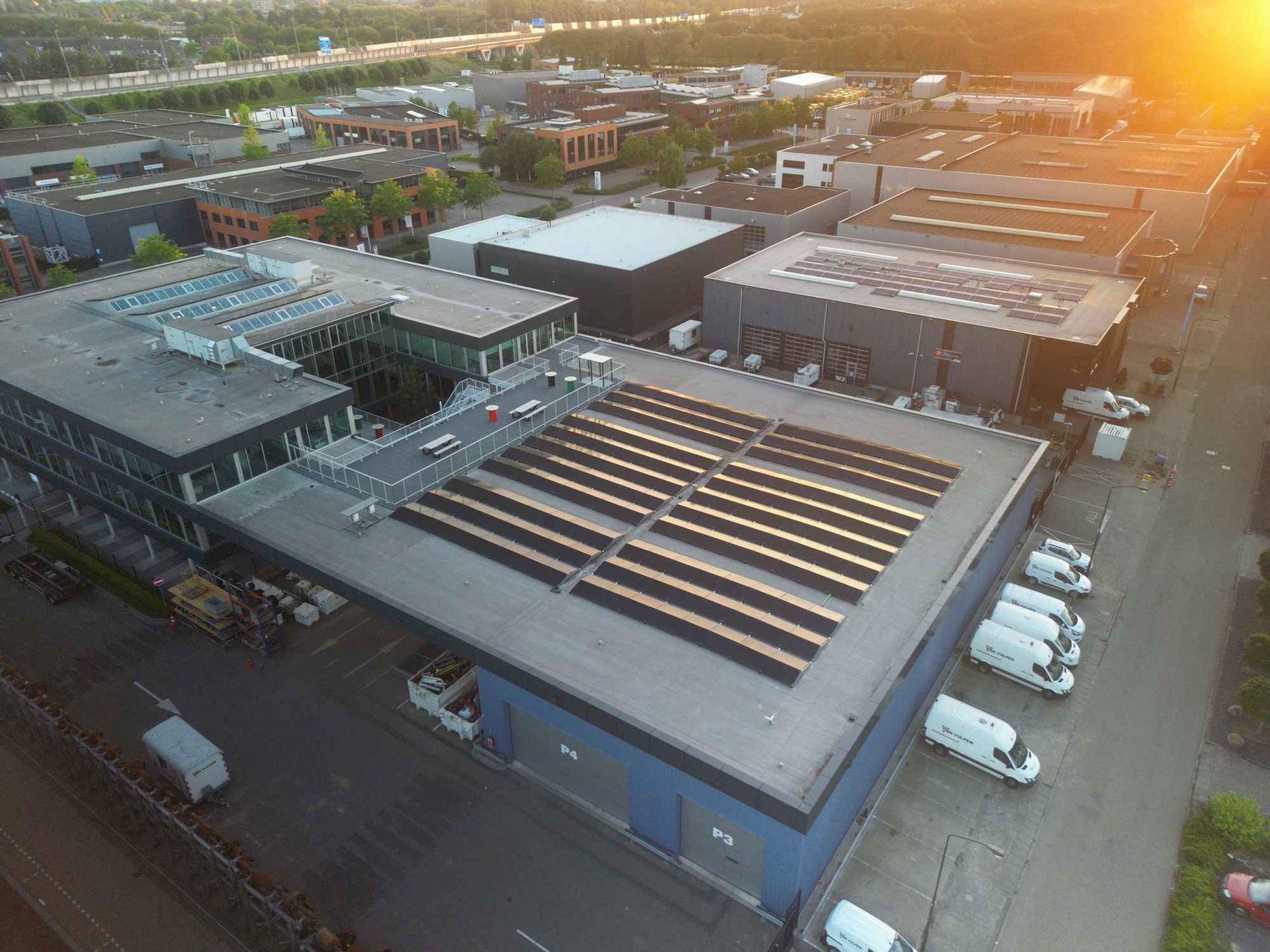 Een luchtfoto van een groot gebouw met zonnepanelen op het dak.