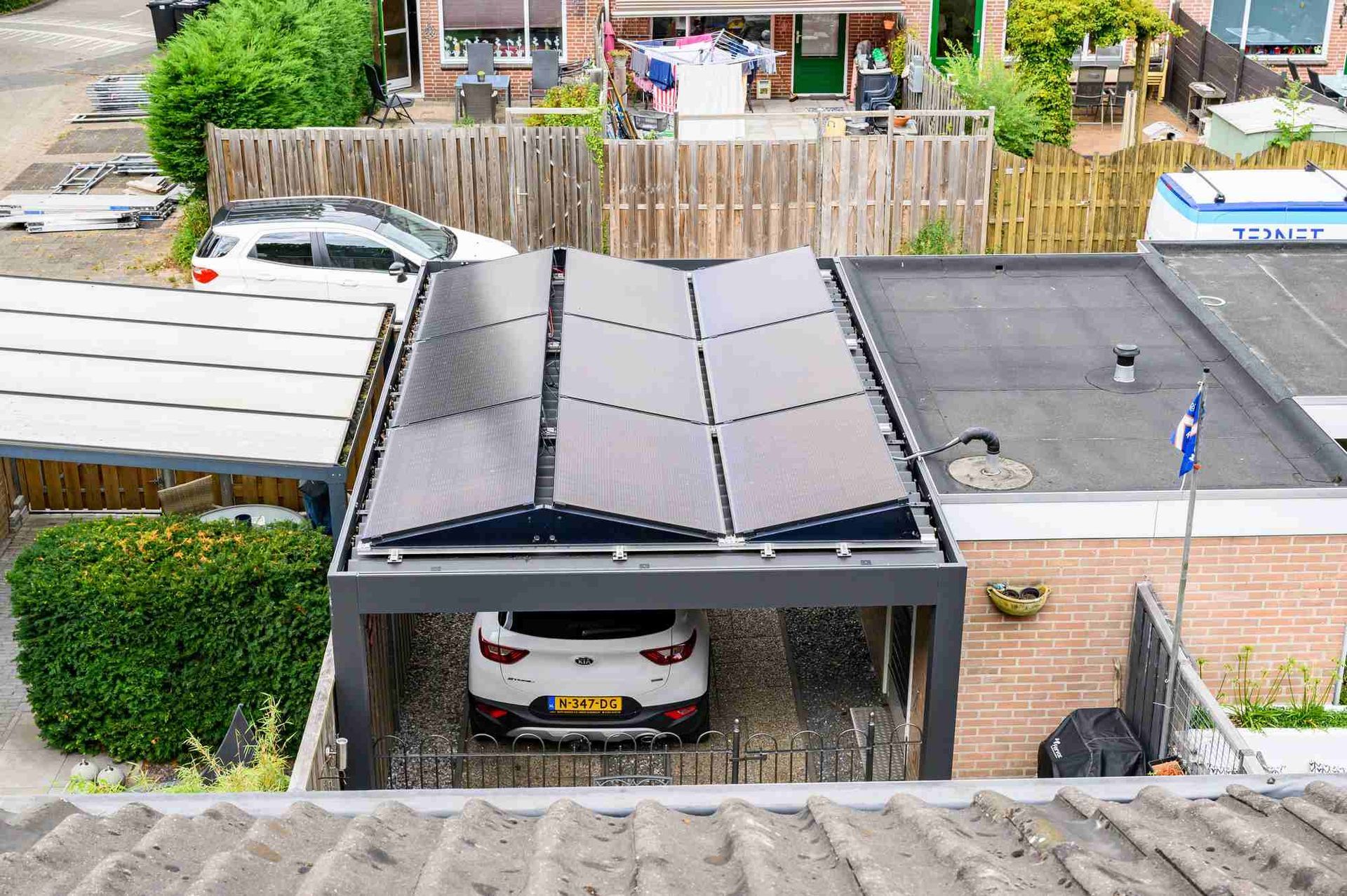 Een auto staat geparkeerd onder een luifel met zonnepanelen op het dak.