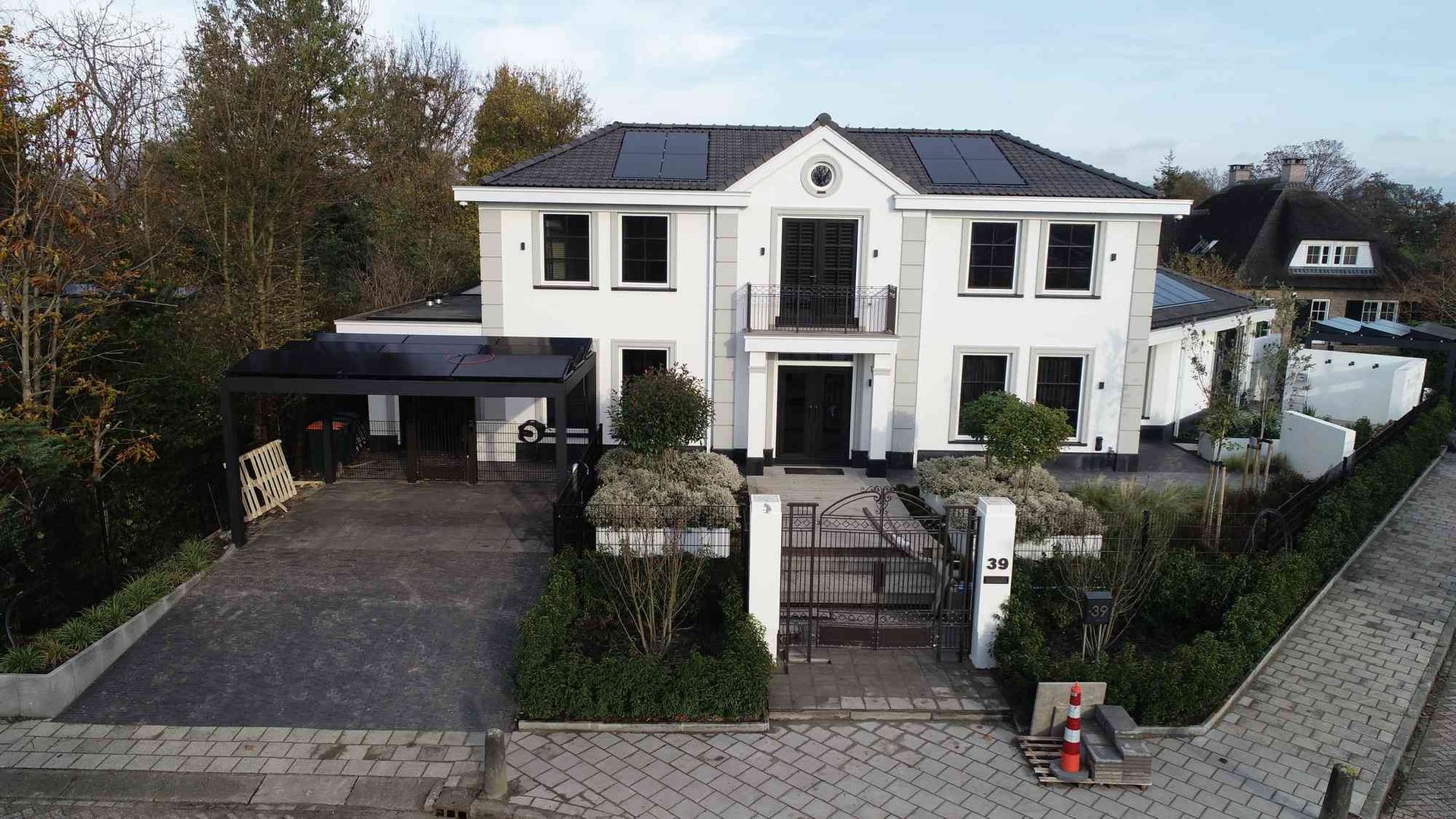 Een luchtfoto van een groot wit huis met zonnepanelen op het dak.