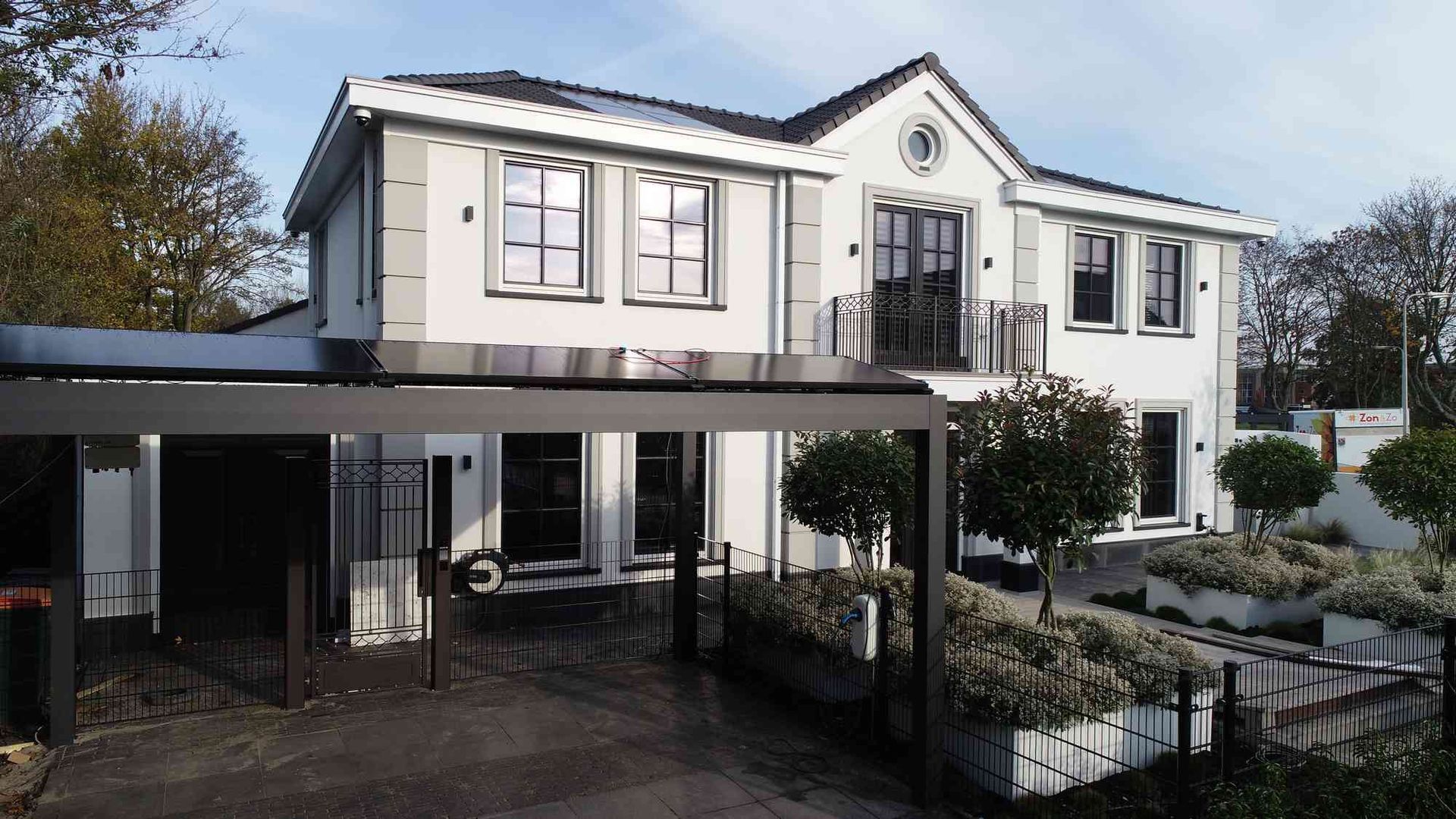 Een groot wit huis met een carport ervoor