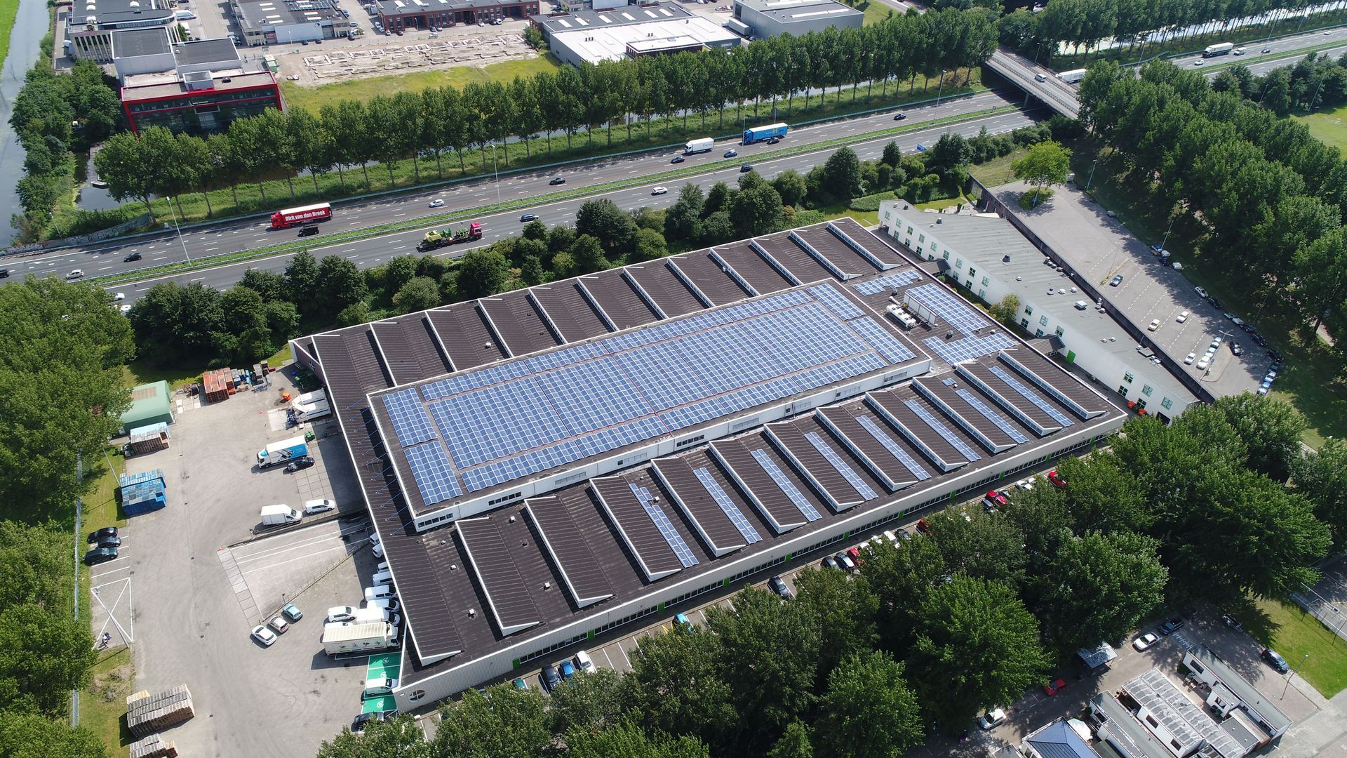 Een luchtfoto van een groot gebouw met zonnepanelen op het dak.