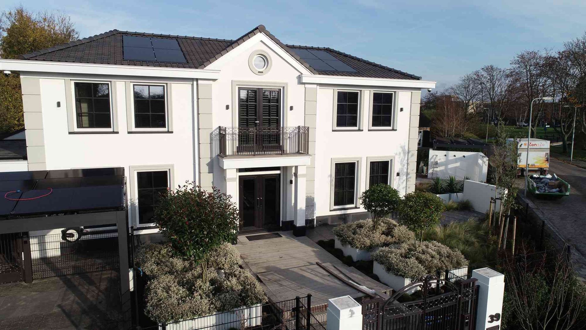 Een luchtfoto van een groot wit huis met zonnepanelen op het dak.