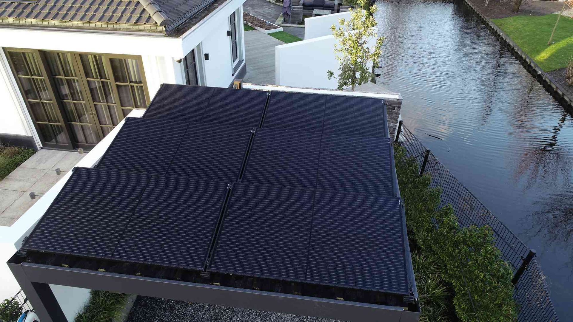 Een luchtfoto van een huis met een zonnepaneel op het dak.