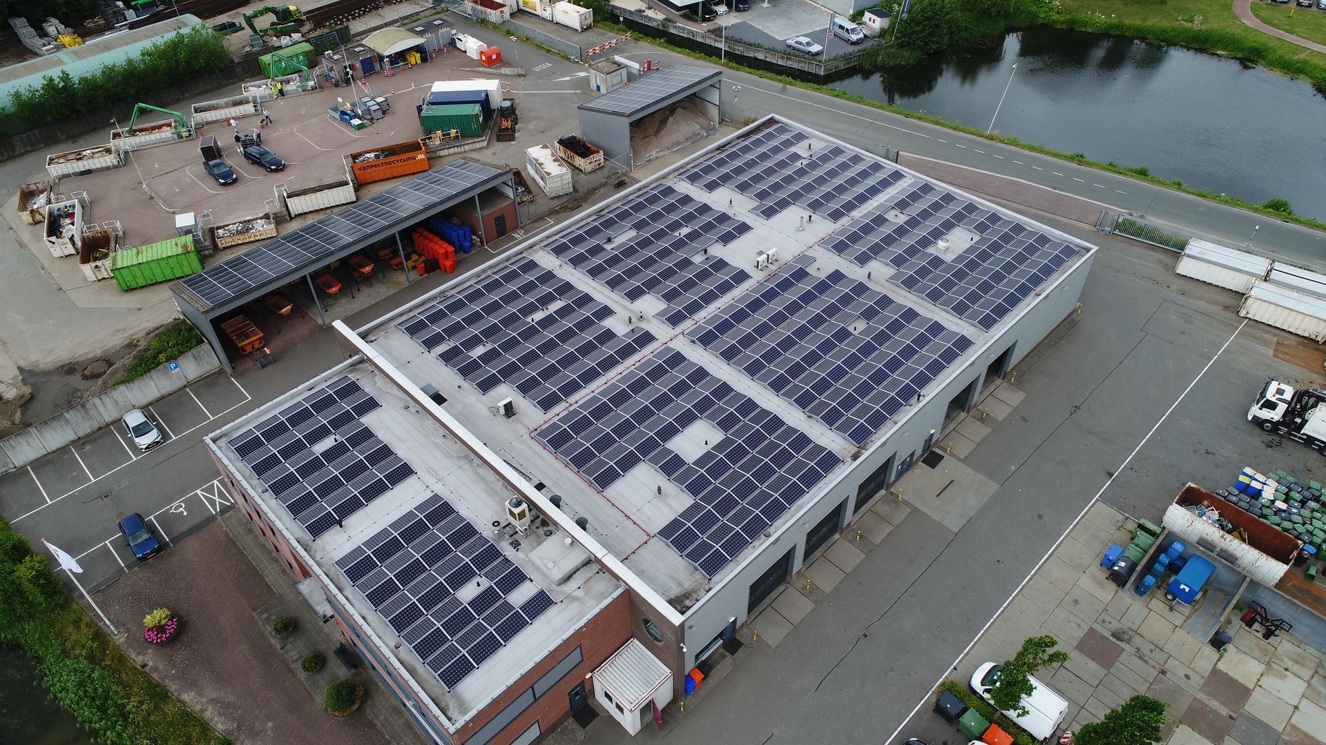 Een luchtfoto van een groot gebouw met zonnepanelen op het dak.