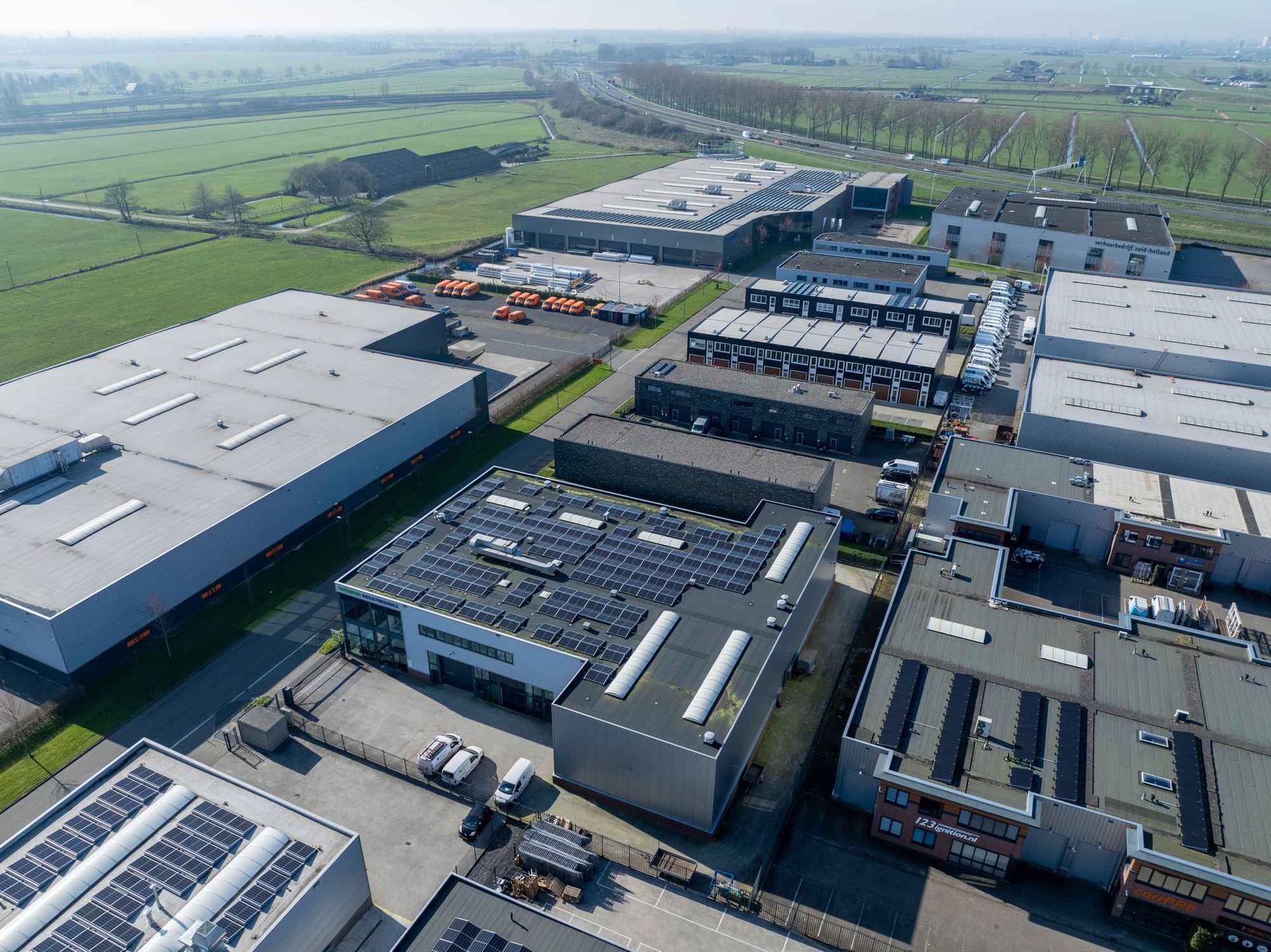 Een luchtfoto van een industriegebied met veel gebouwen en zonnepanelen op de daken.