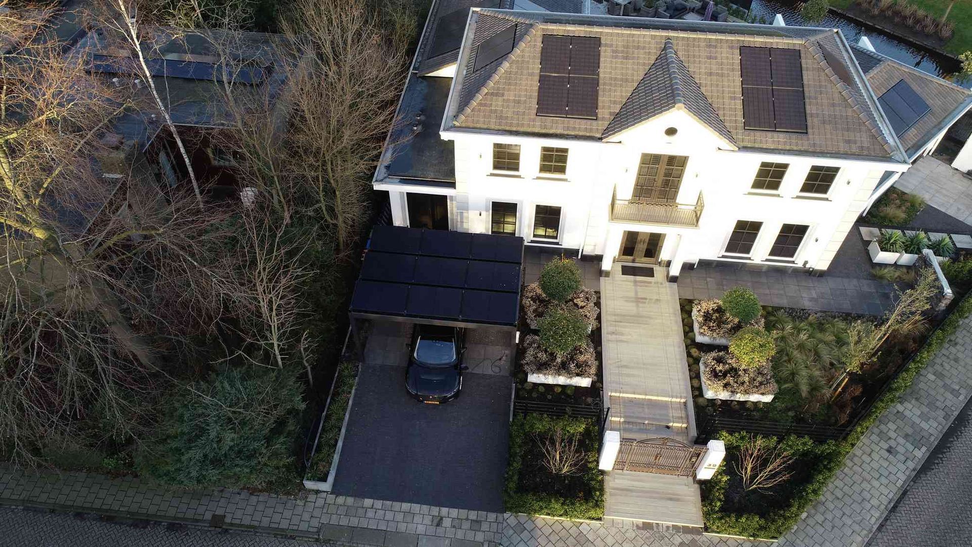 Een luchtfoto van een groot wit huis met een auto ervoor geparkeerd.