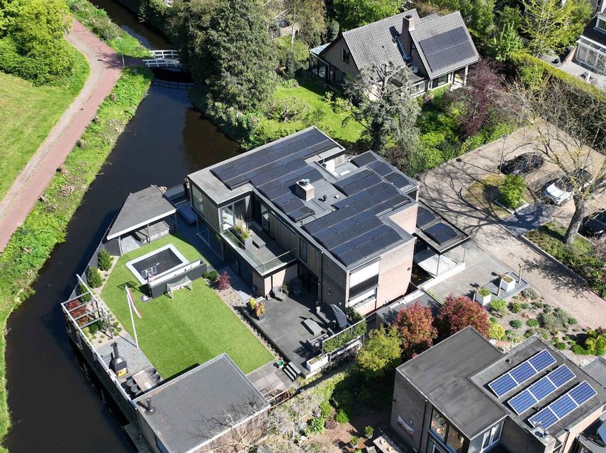 Een luchtfoto van een huis met zonnepanelen op het dak.