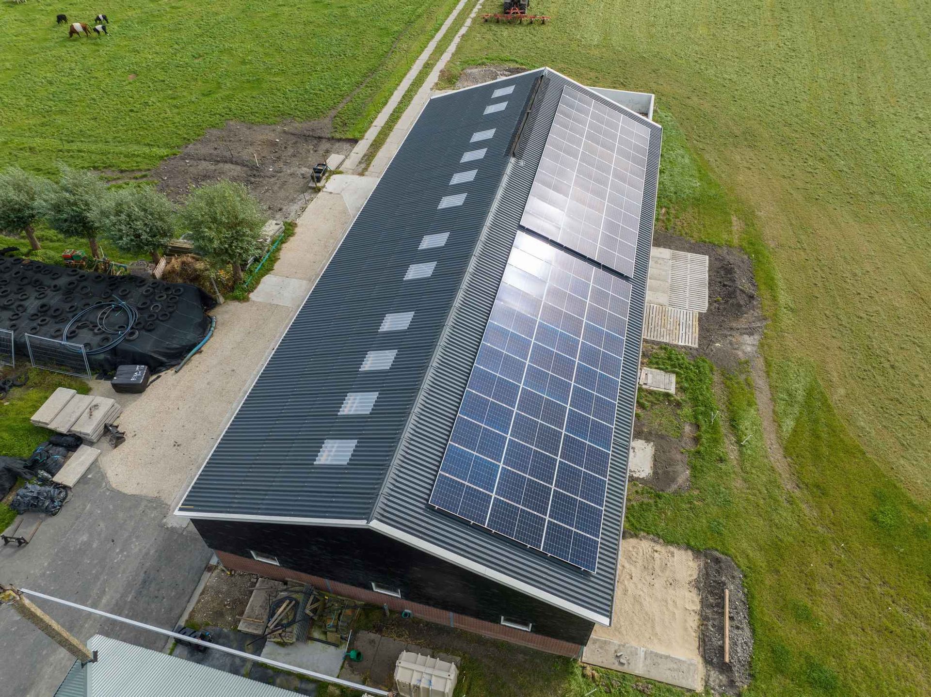 Een luchtfoto van een schuur met zonnepanelen op het dak.