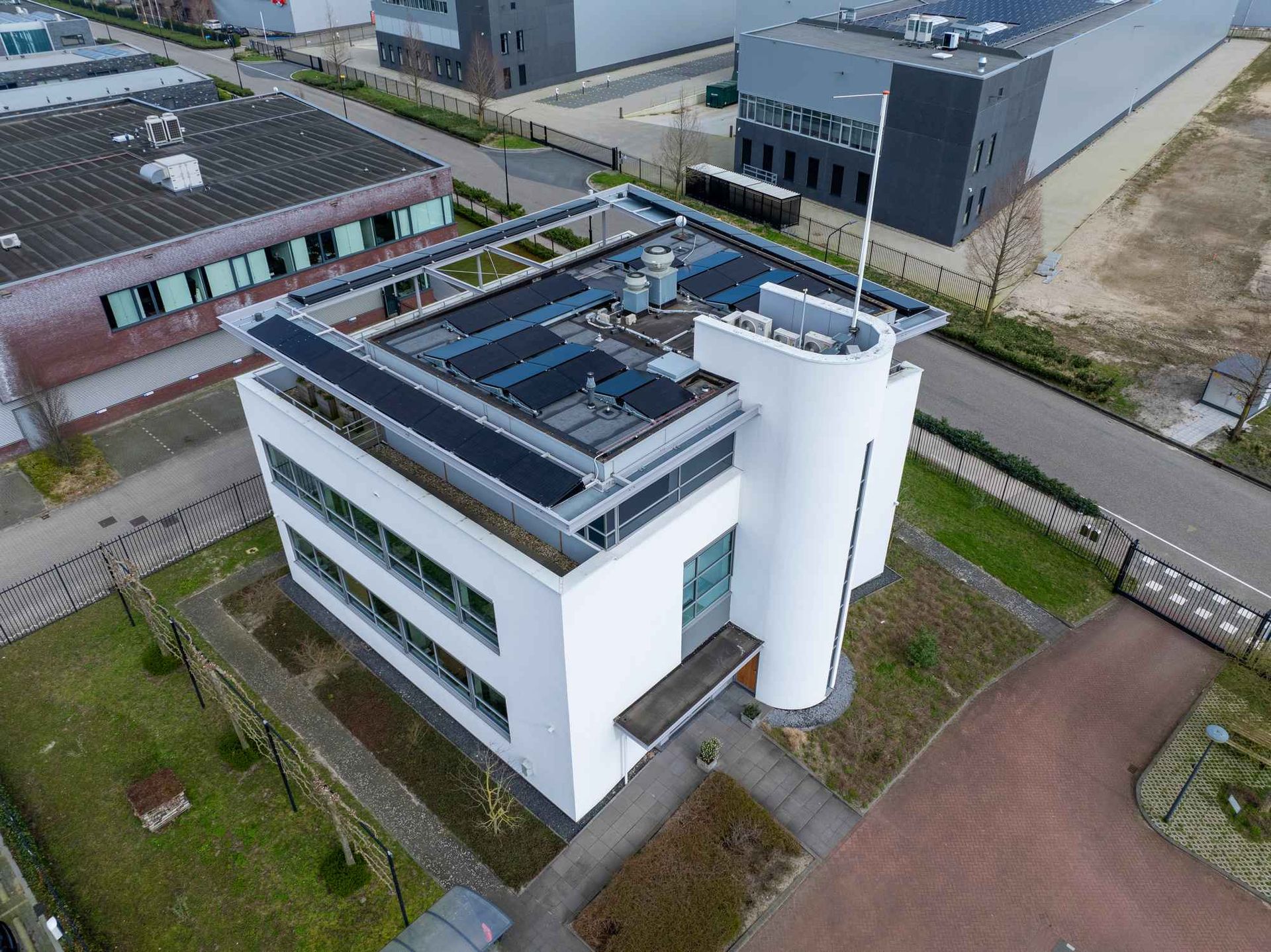 Een luchtfoto van een groot wit gebouw met zonnepanelen op het dak.