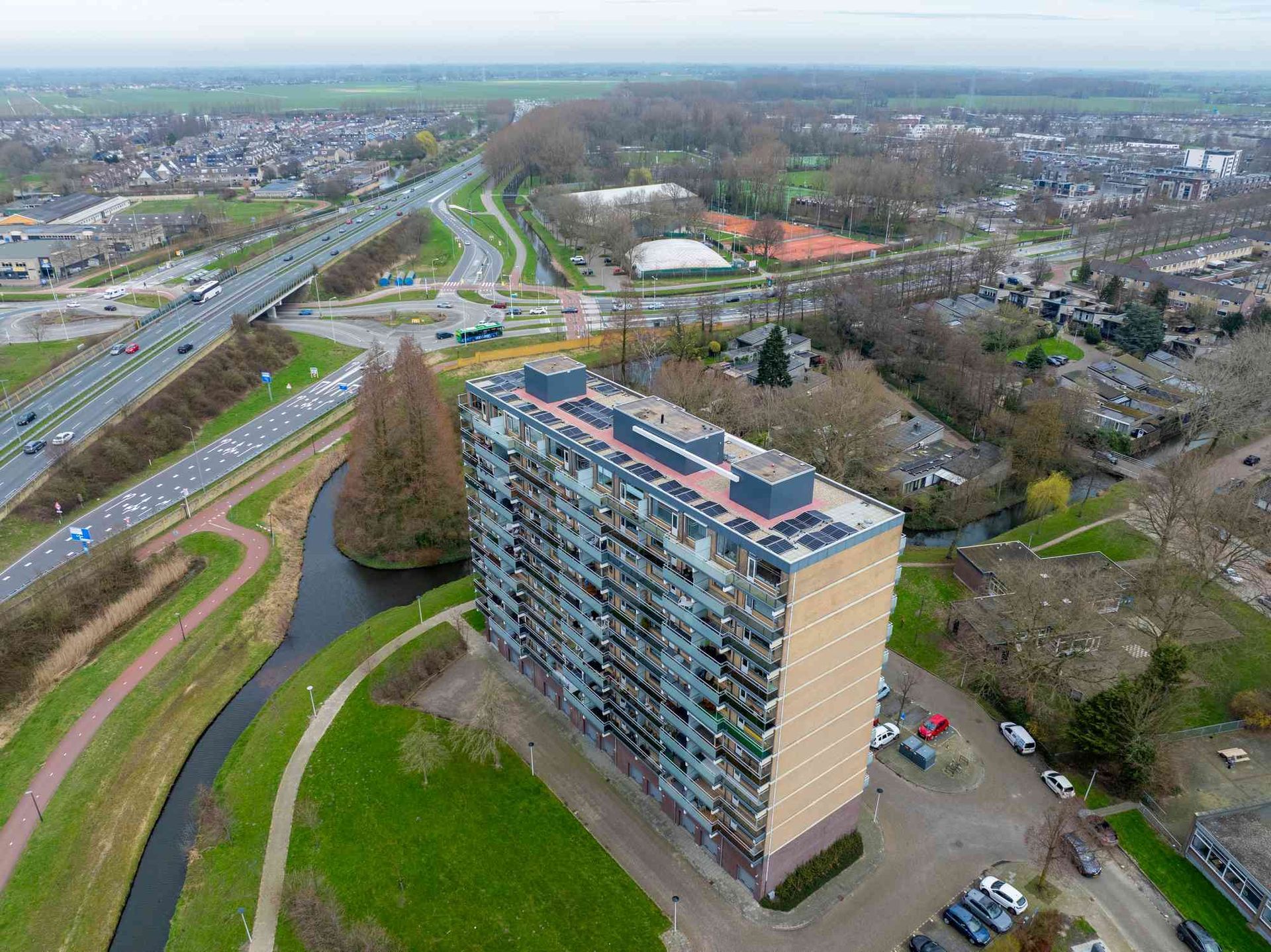 Een luchtfoto van een groot appartementengebouw met zonnepanelen op het dak.