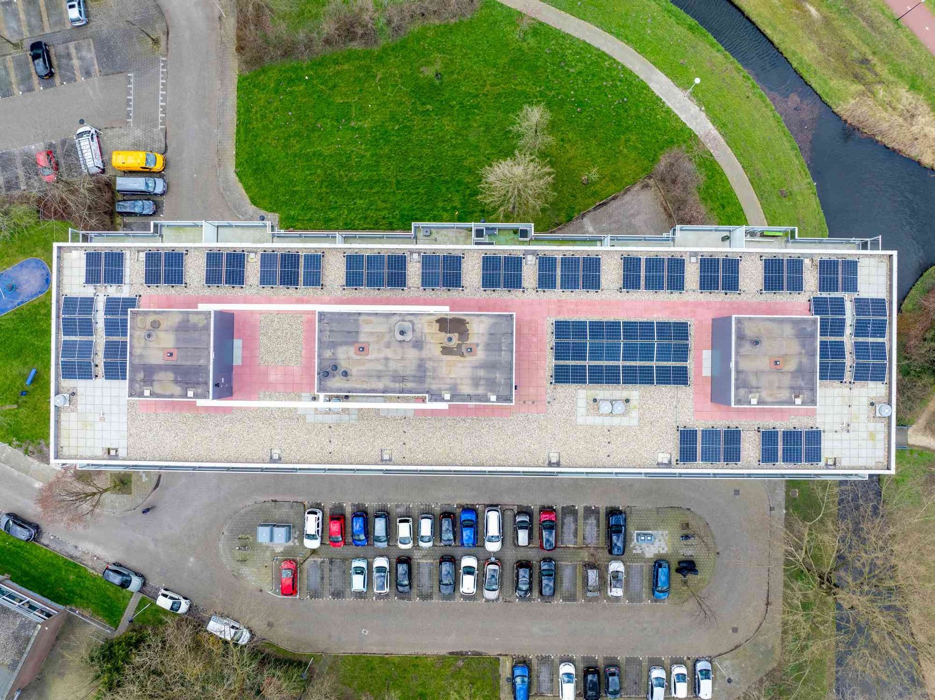 Een luchtfoto van een groot gebouw met zonnepanelen op het dak.