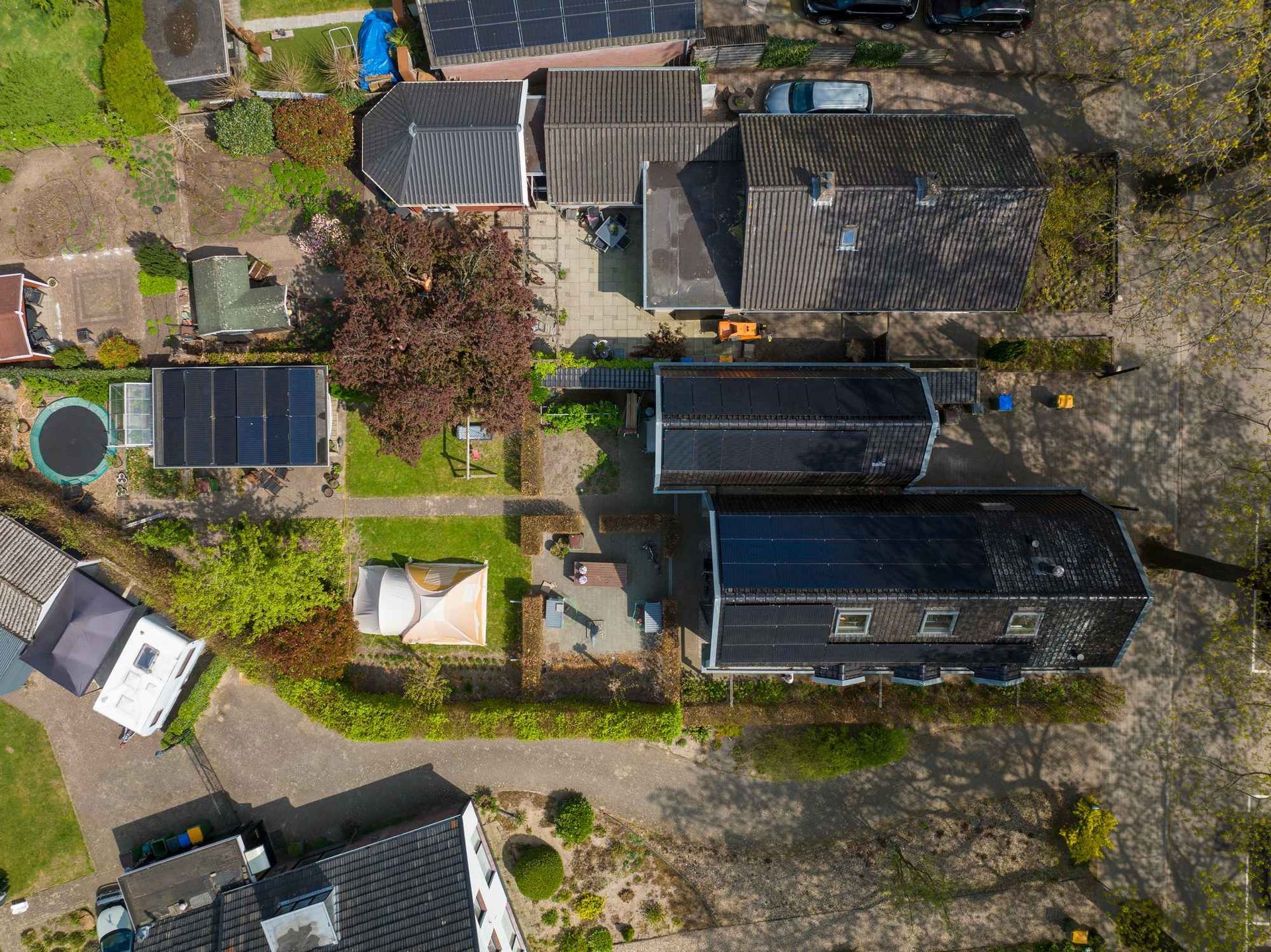 Een luchtfoto van een woonwijk met veel huizen en zonnepanelen op de daken.