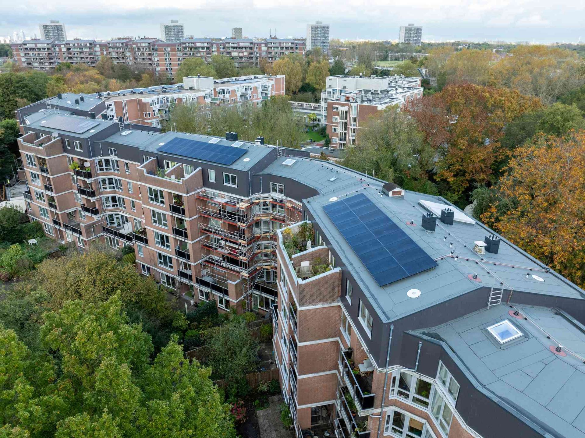 Een luchtfoto van een groot appartementengebouw met zonnepanelen op het dak.