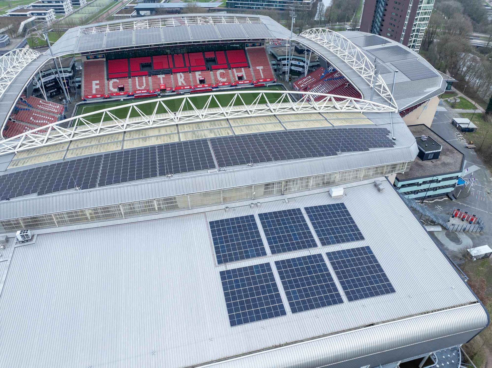 Een luchtfoto van een stadion met zonnepanelen op het dak.