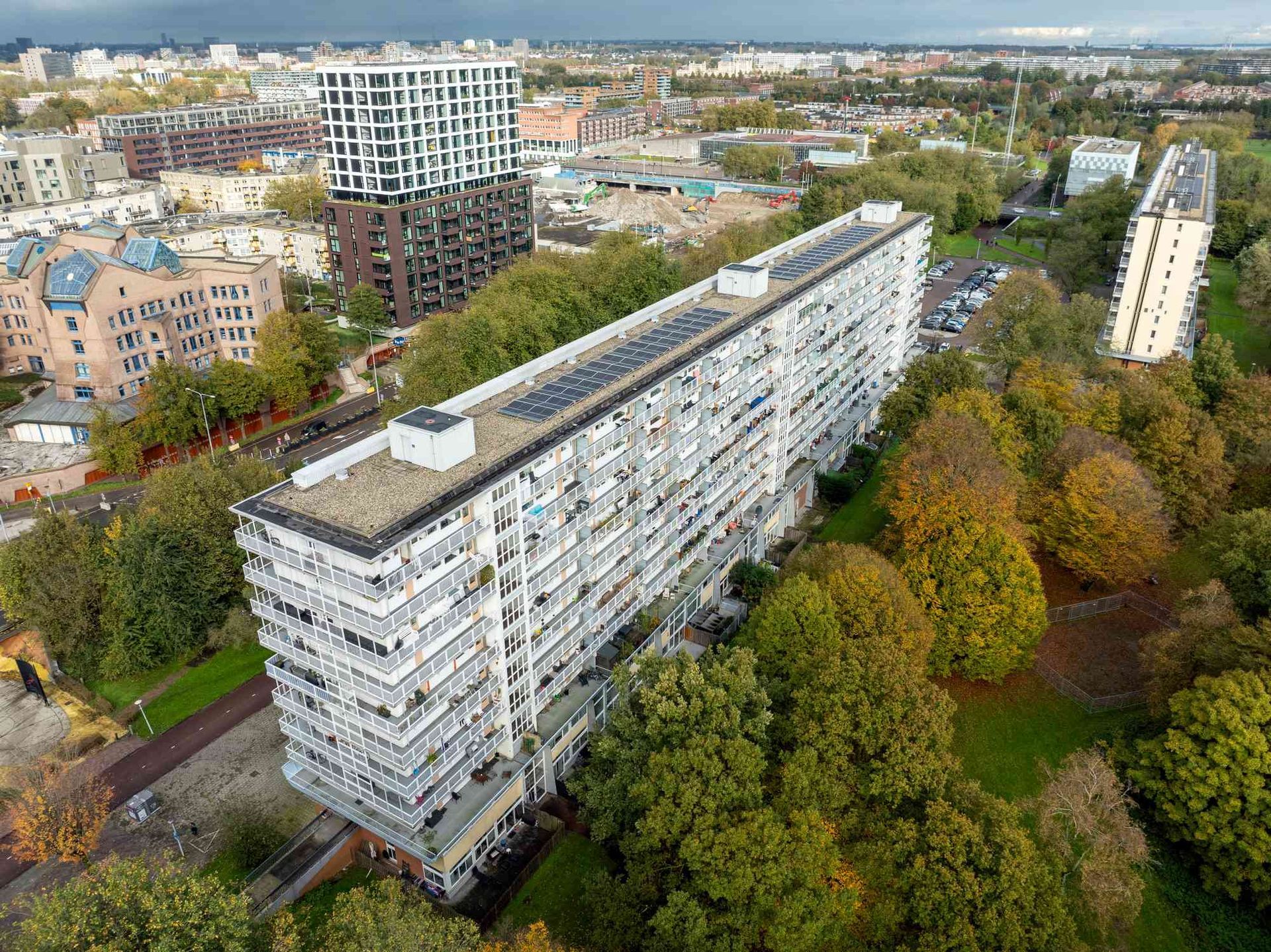 Een luchtfoto van een groot appartementengebouw in een stad, omgeven door bomen.