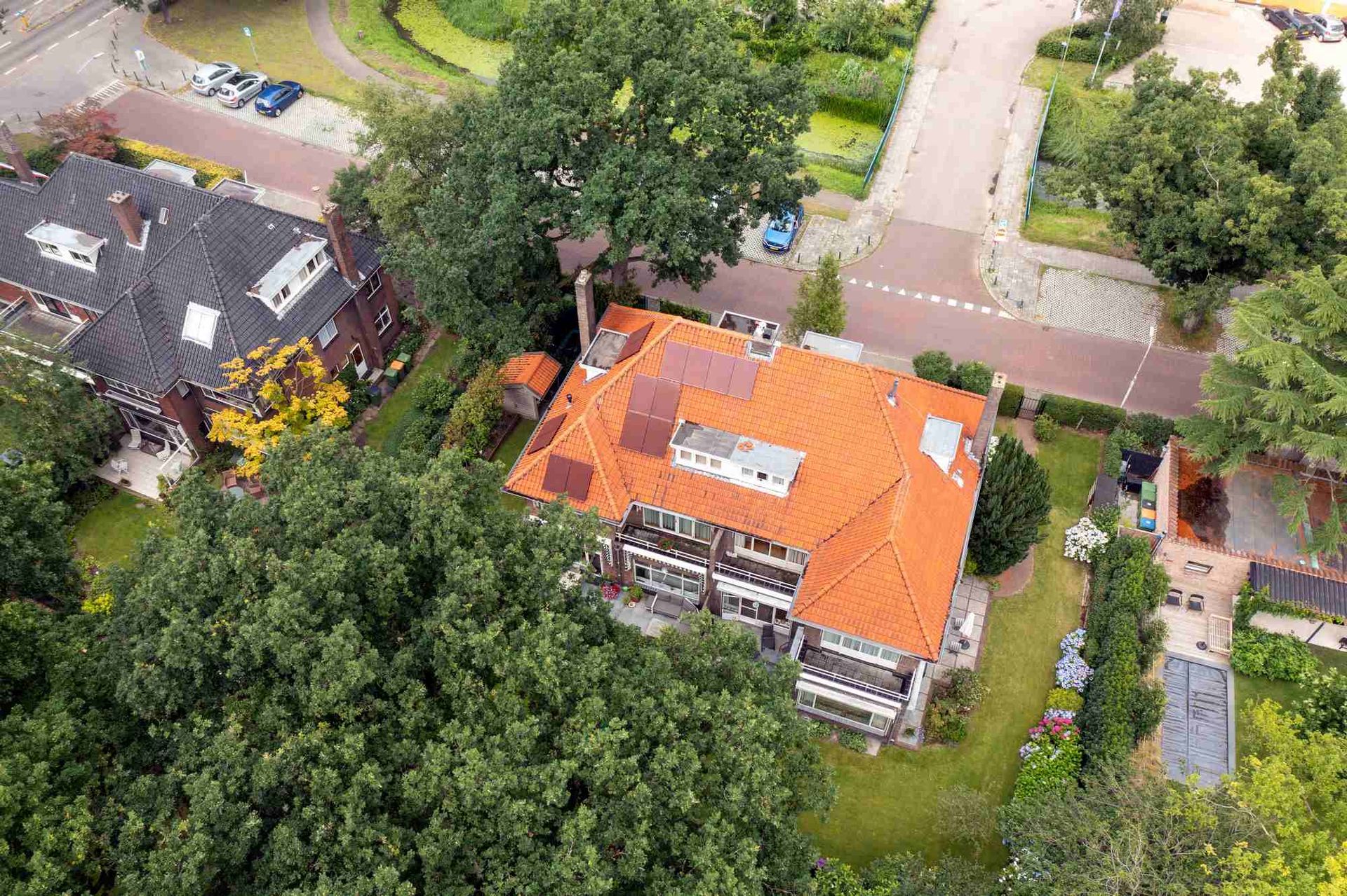 Een luchtfoto van een huis met een rood dak, omgeven door bomen.