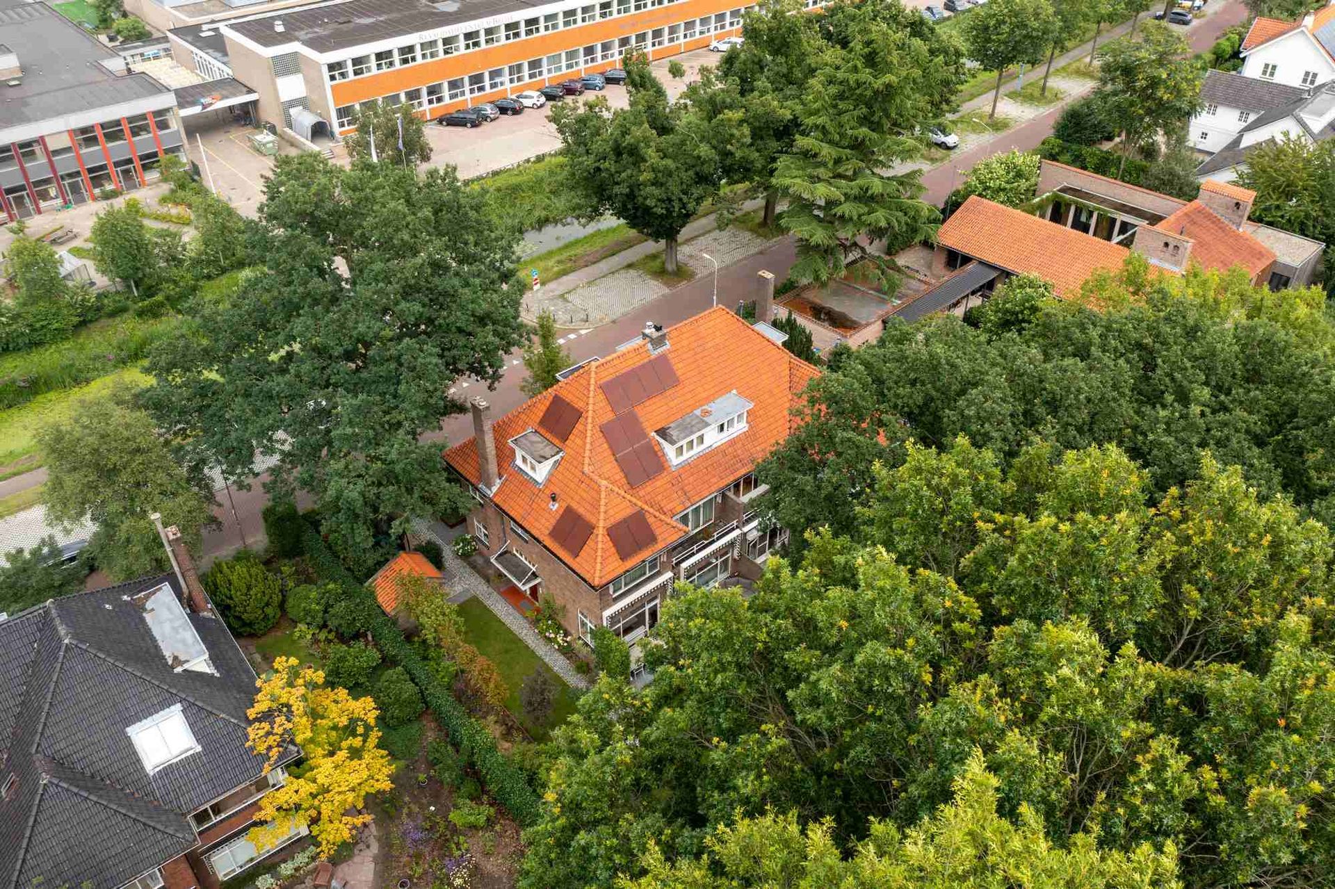 Een luchtfoto van een huis met een rood dak, omgeven door bomen.
