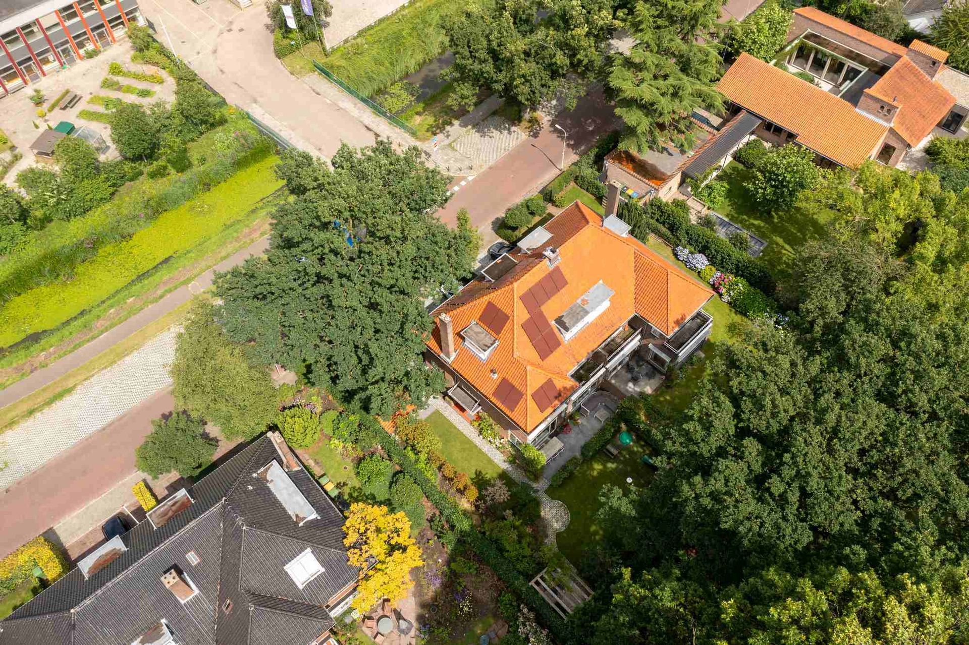 Een luchtfoto van een huis met een rood dak, omgeven door bomen.