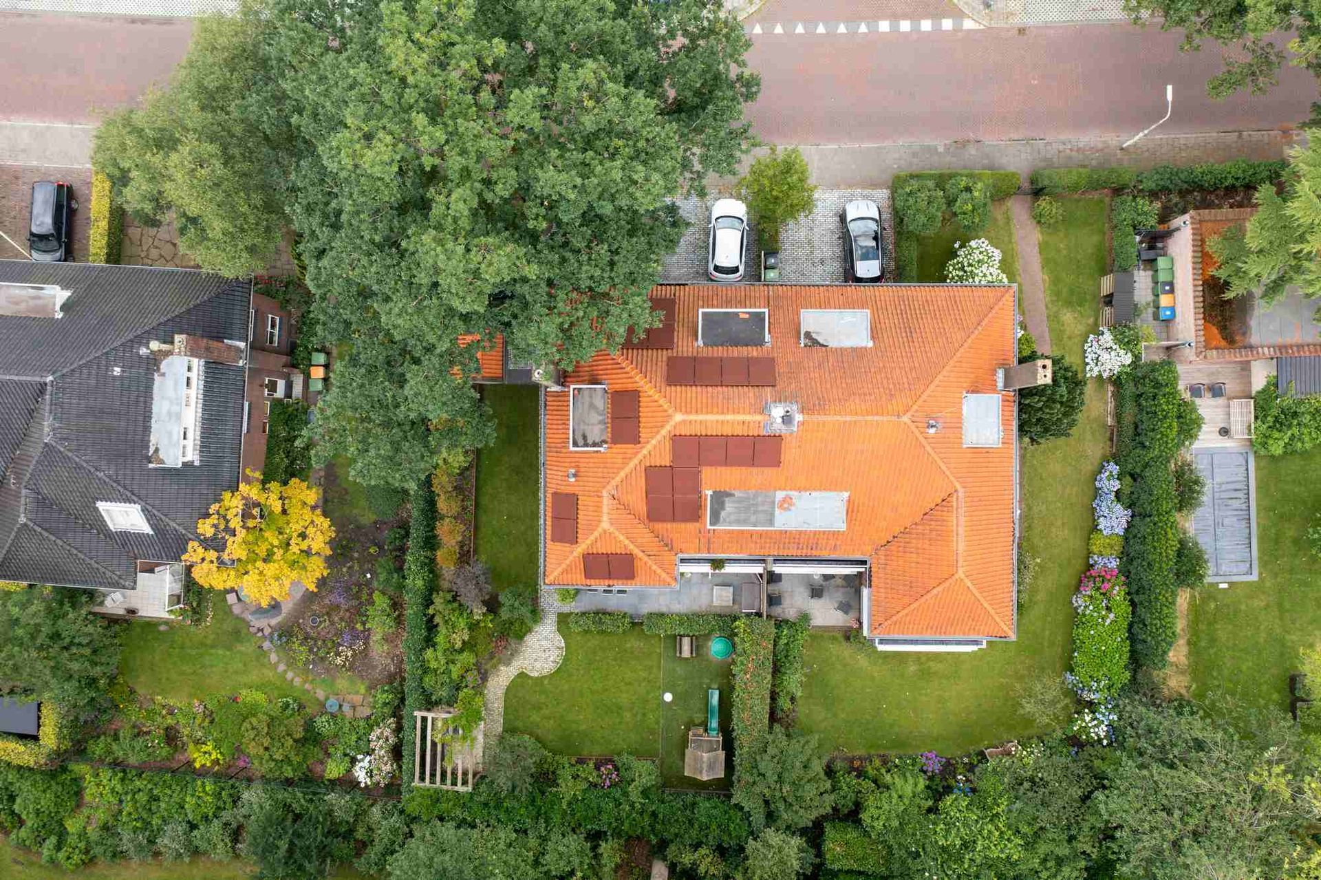 Een luchtfoto van een huis met een rood dak, omgeven door bomen.