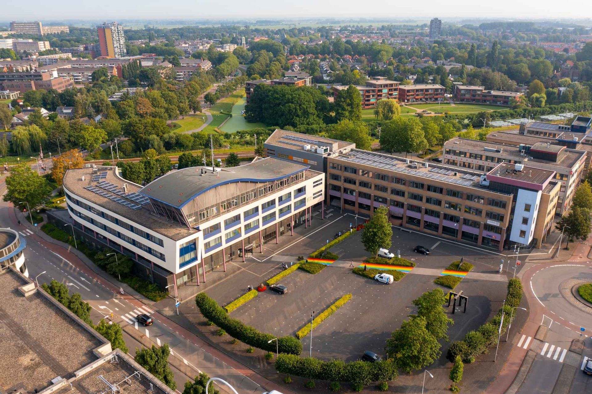Een luchtfoto van een groot gebouw met een parkeerplaats ervoor.