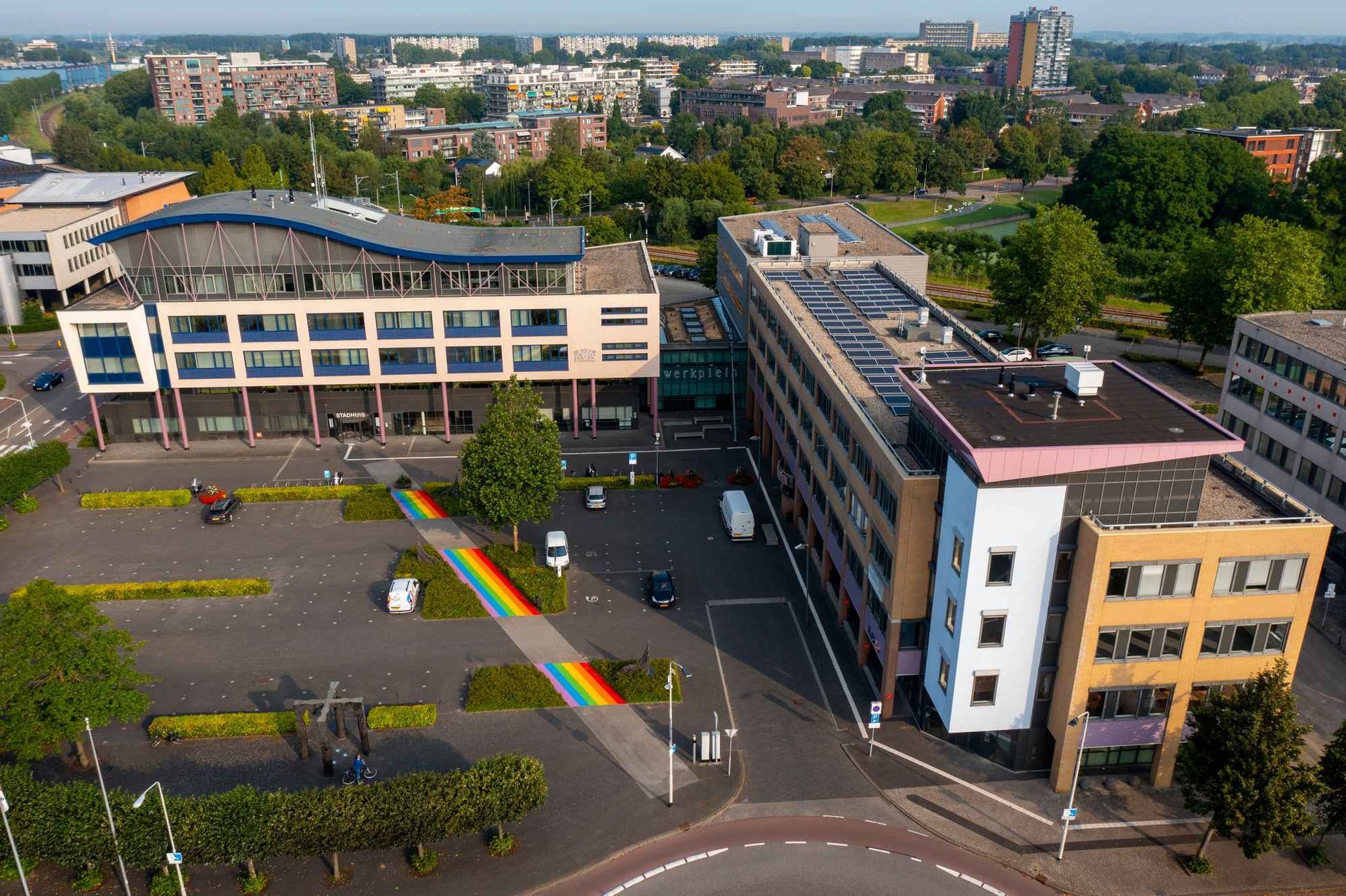 Een luchtfoto van een groot gebouw met een regenboog ervoor.