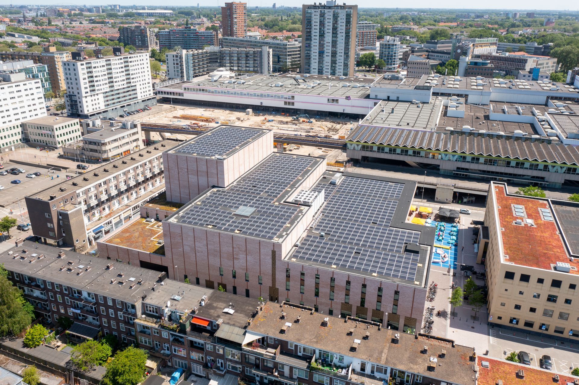 Een luchtfoto van een stad met een groot gebouw met zonnepanelen op het dak.