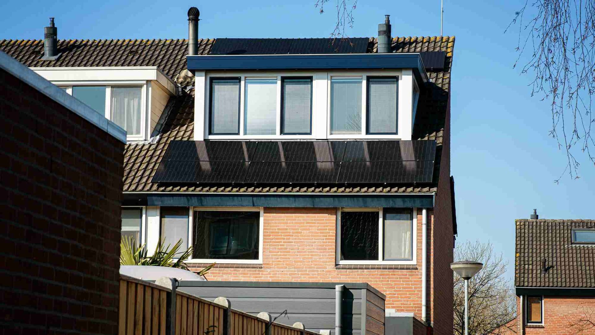 Een bakstenen huis met zonnepanelen op het dak.