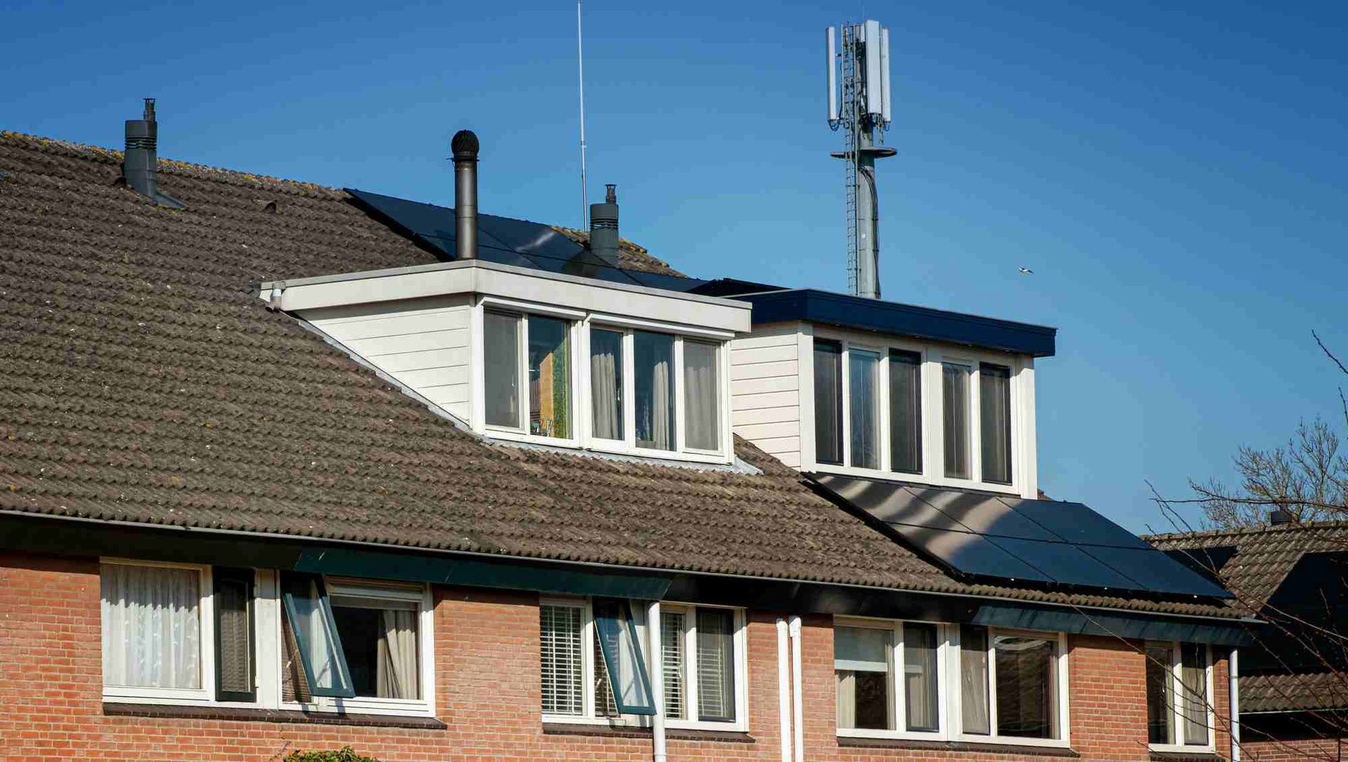 Een bakstenen huis met daarop een windturbine.