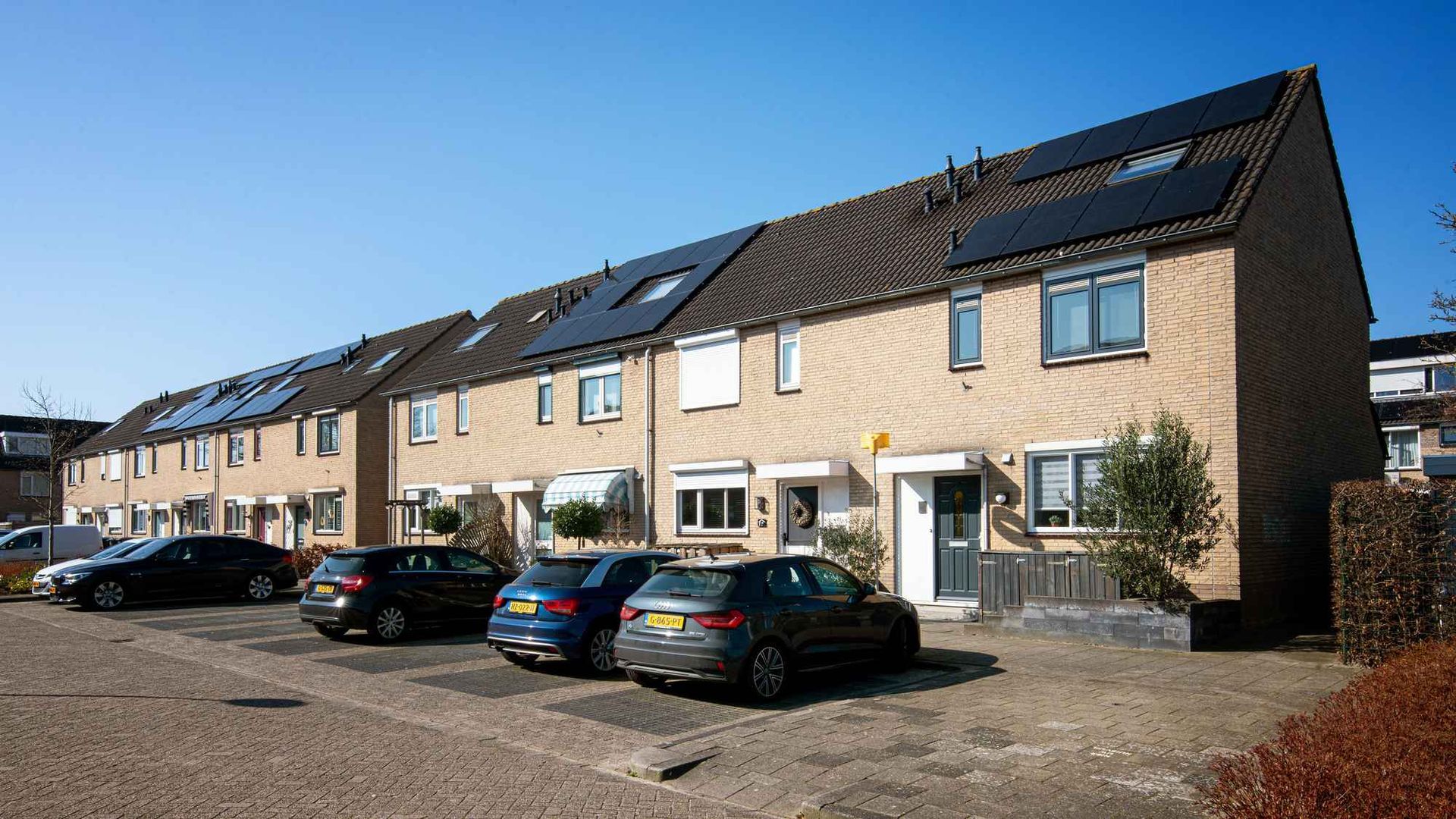 Een rij huizen met ervoor geparkeerde auto's.