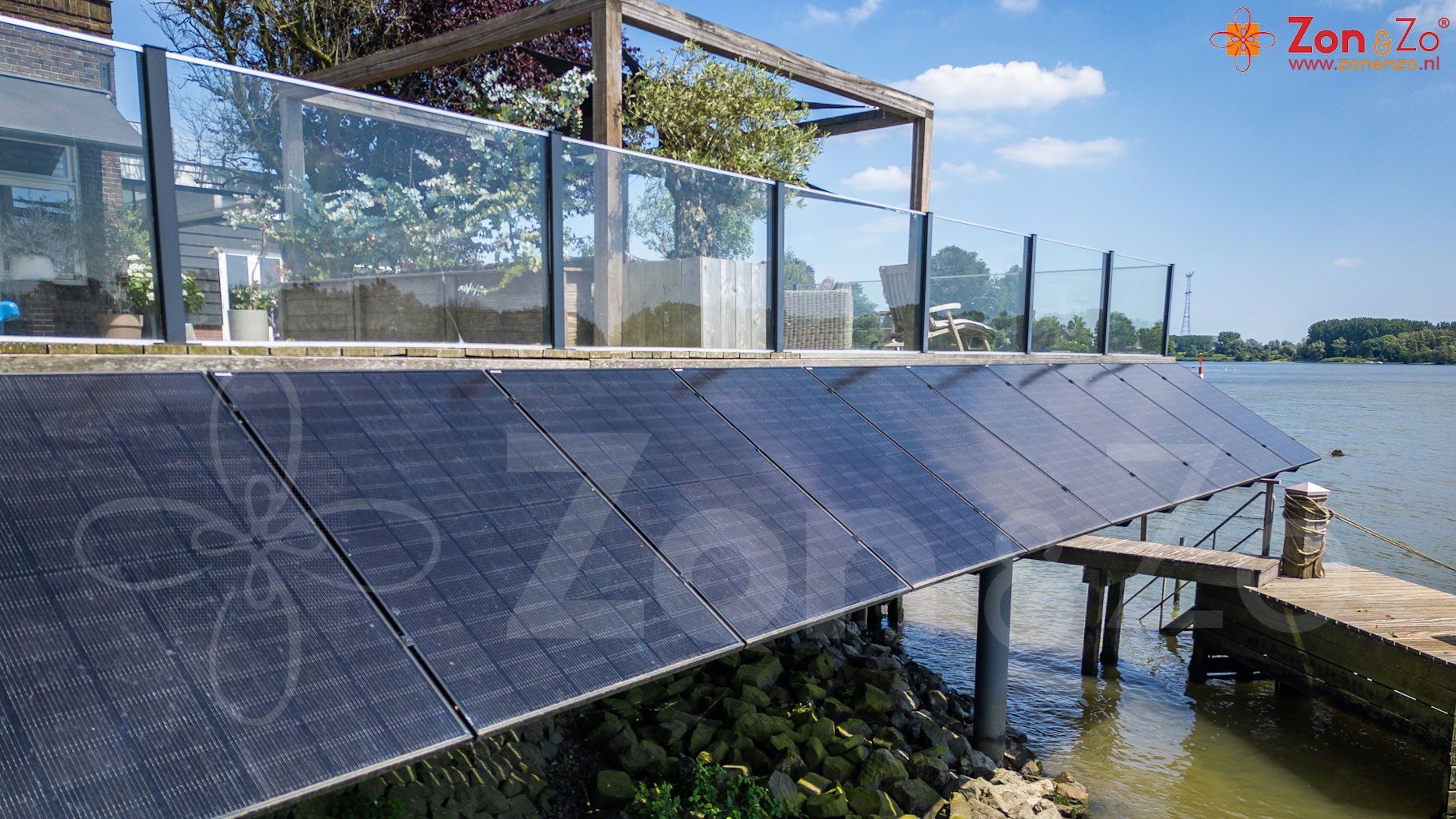 Een rij zonnepanelen op een steiger naast een waterpartij.