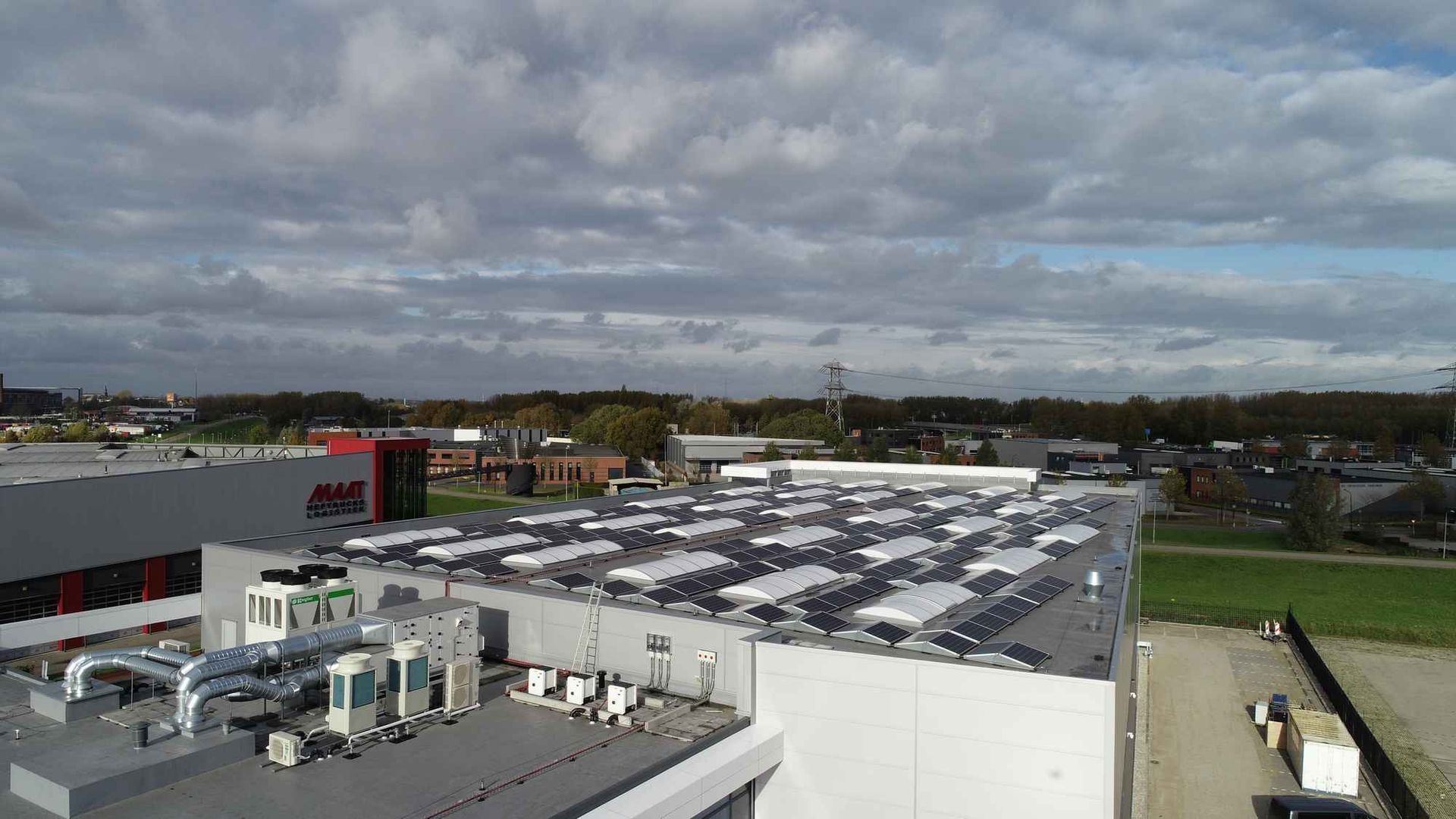 Een luchtfoto van een groot gebouw met veel zonnepanelen op het dak.