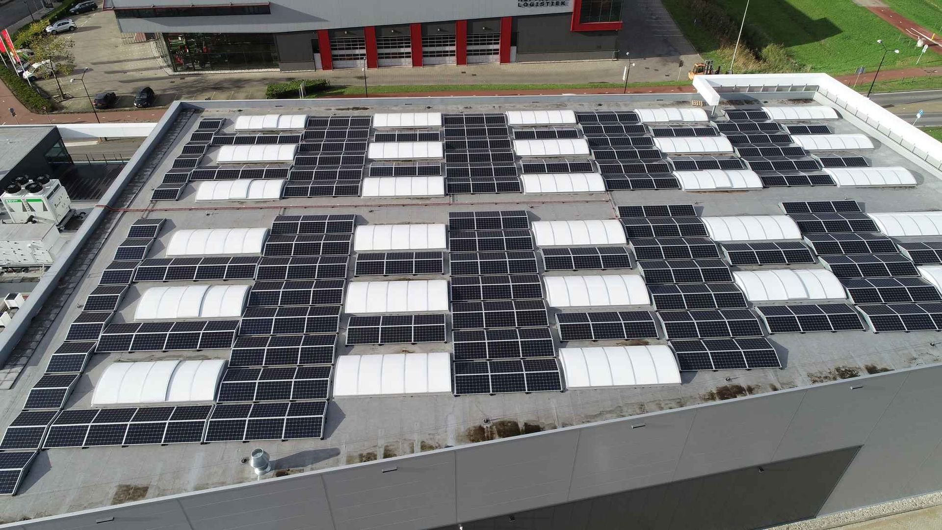 Een groot gebouw met veel zonnepanelen op het dak.