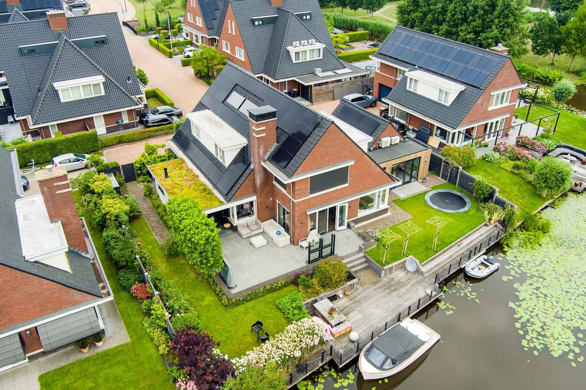 Een luchtfoto van een woonwijk met huizen en een boot in het water.