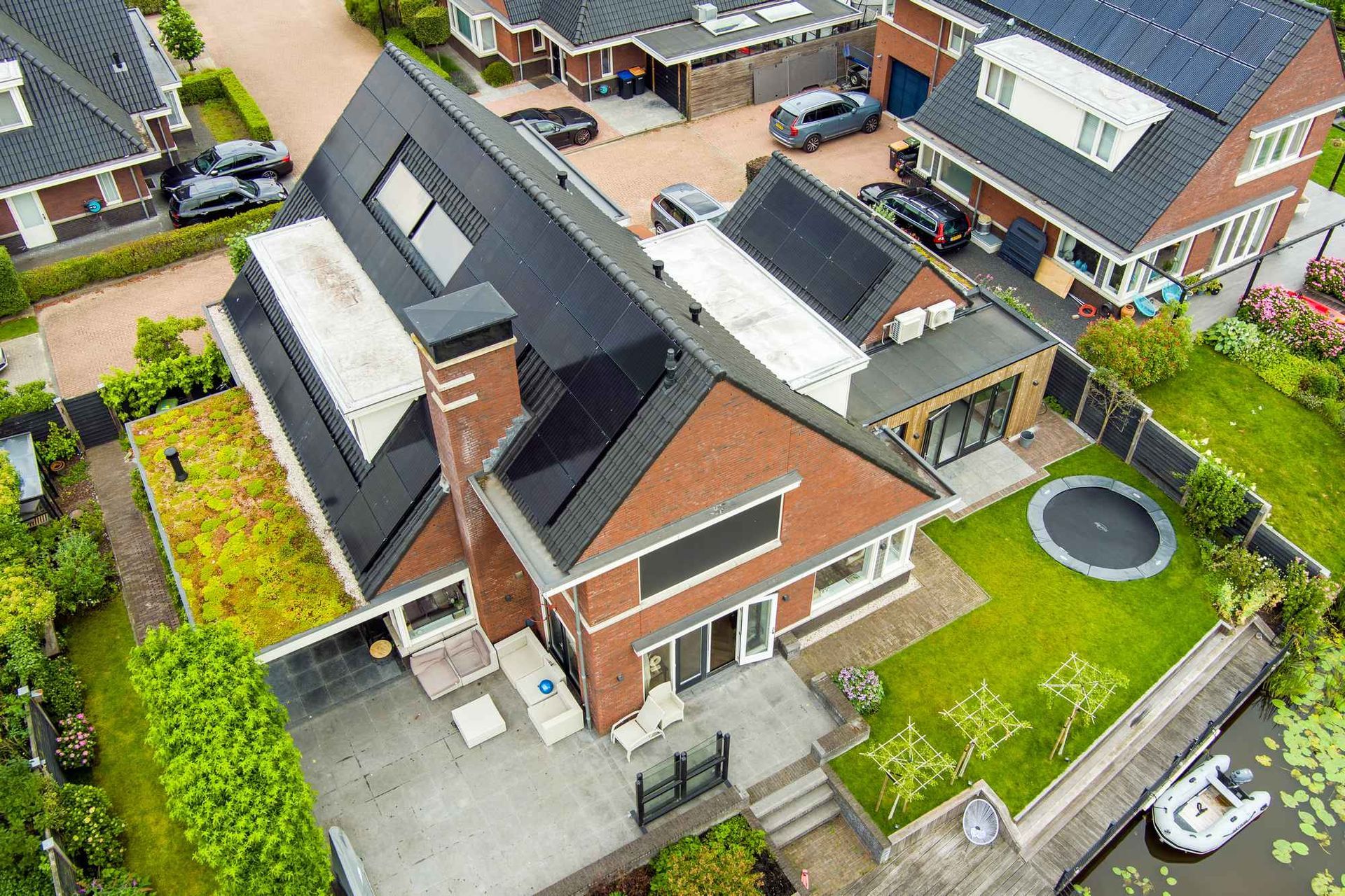 Een luchtfoto van een bakstenen huis met zonnepanelen op het dak.