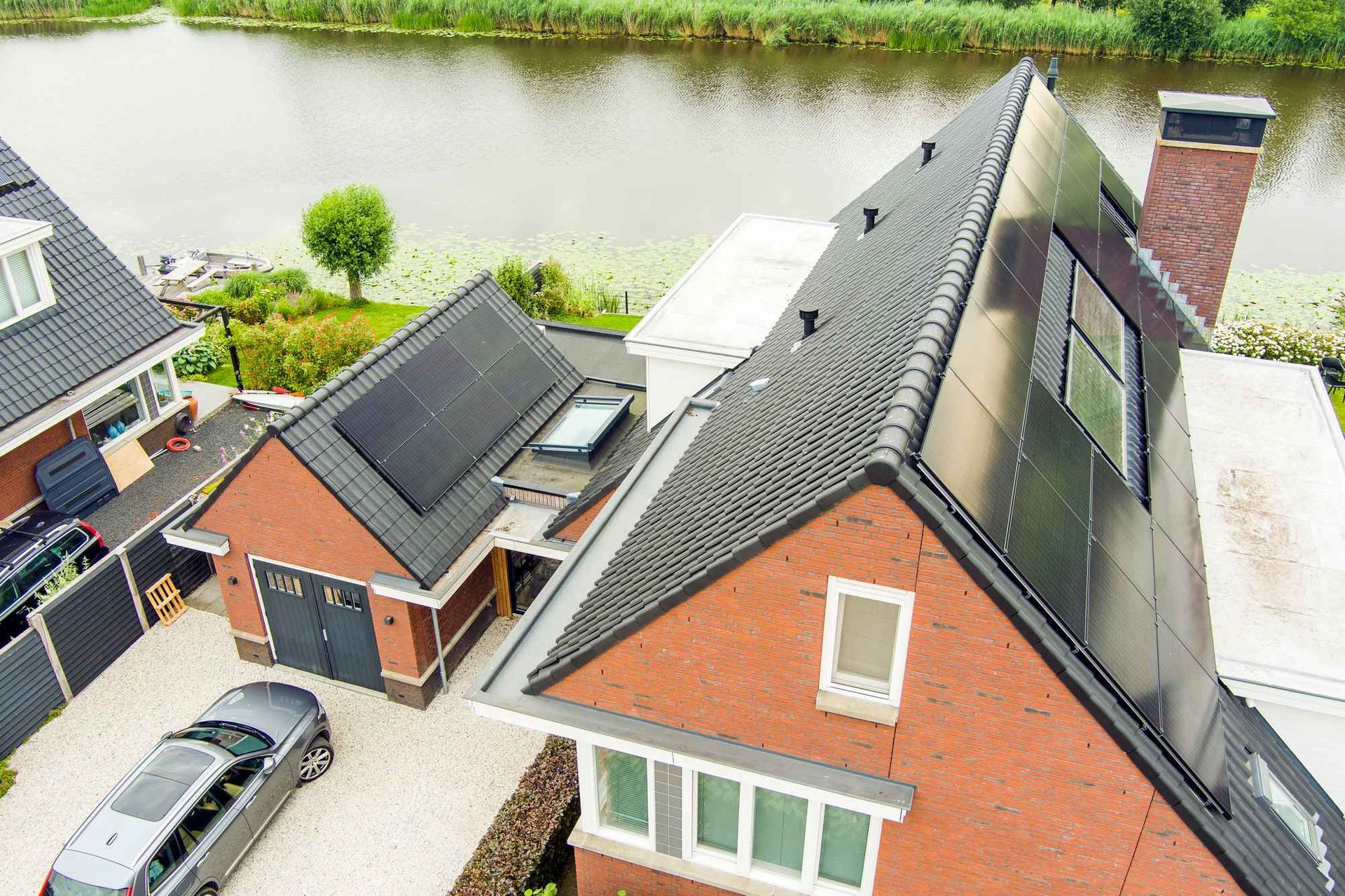 Een luchtfoto van een bakstenen huis met zonnepanelen op het dak.