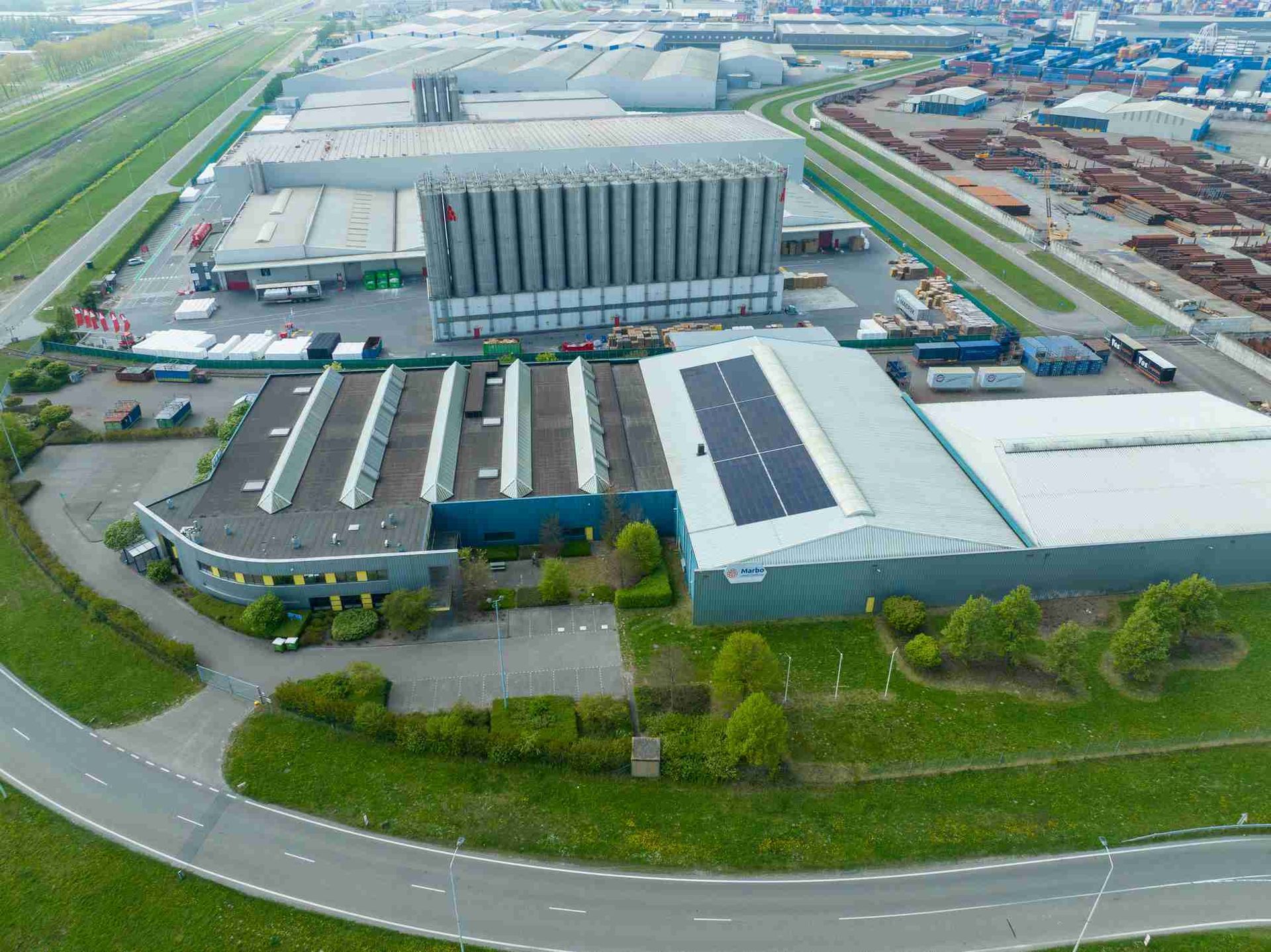 Een luchtfoto van een groot magazijn met zonnepanelen op het dak.